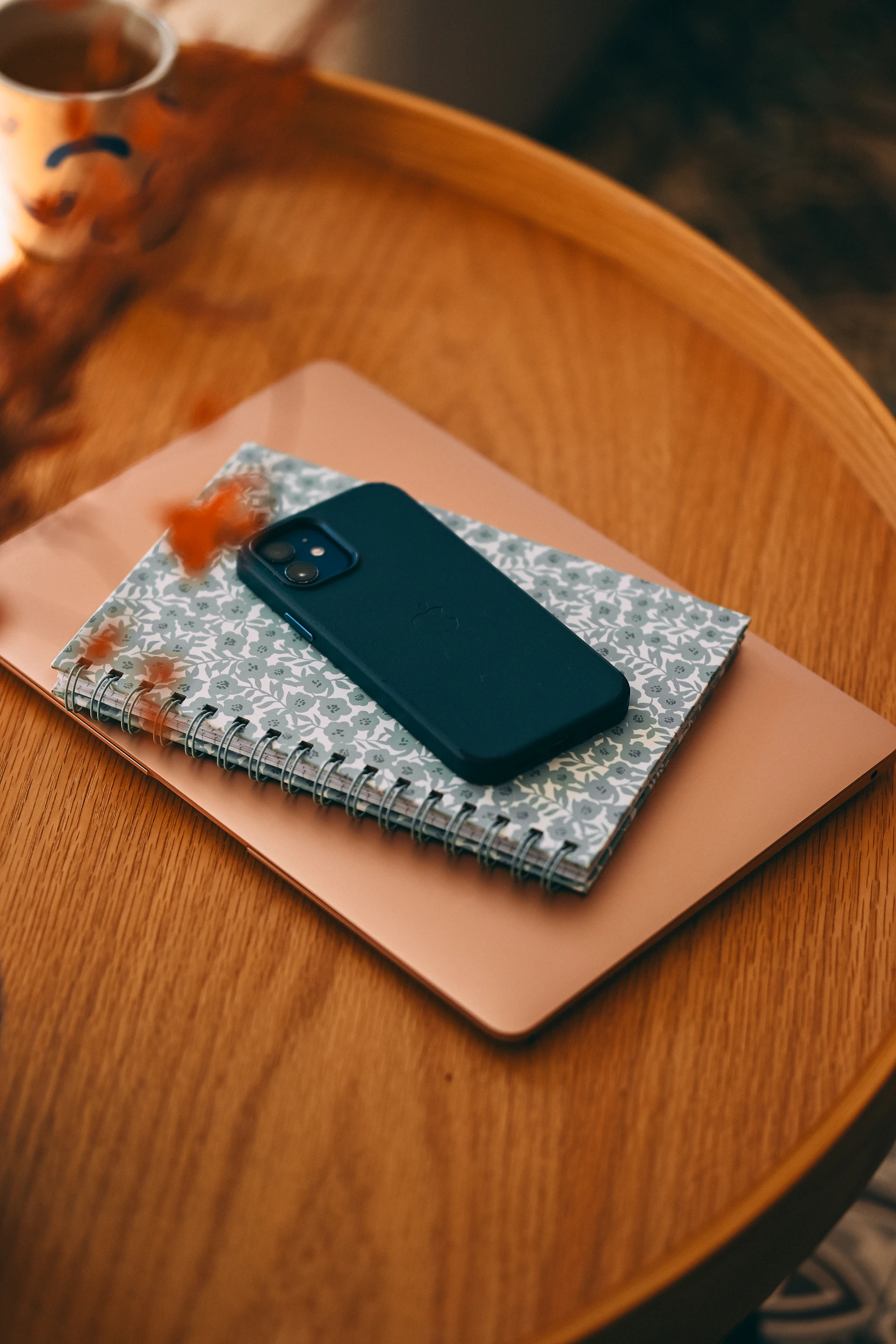 Smartphone resting on a notebook beside a laptop on a modern desk