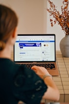 Woman using a laptop with social media open.