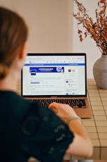 Woman using a laptop with social media open.