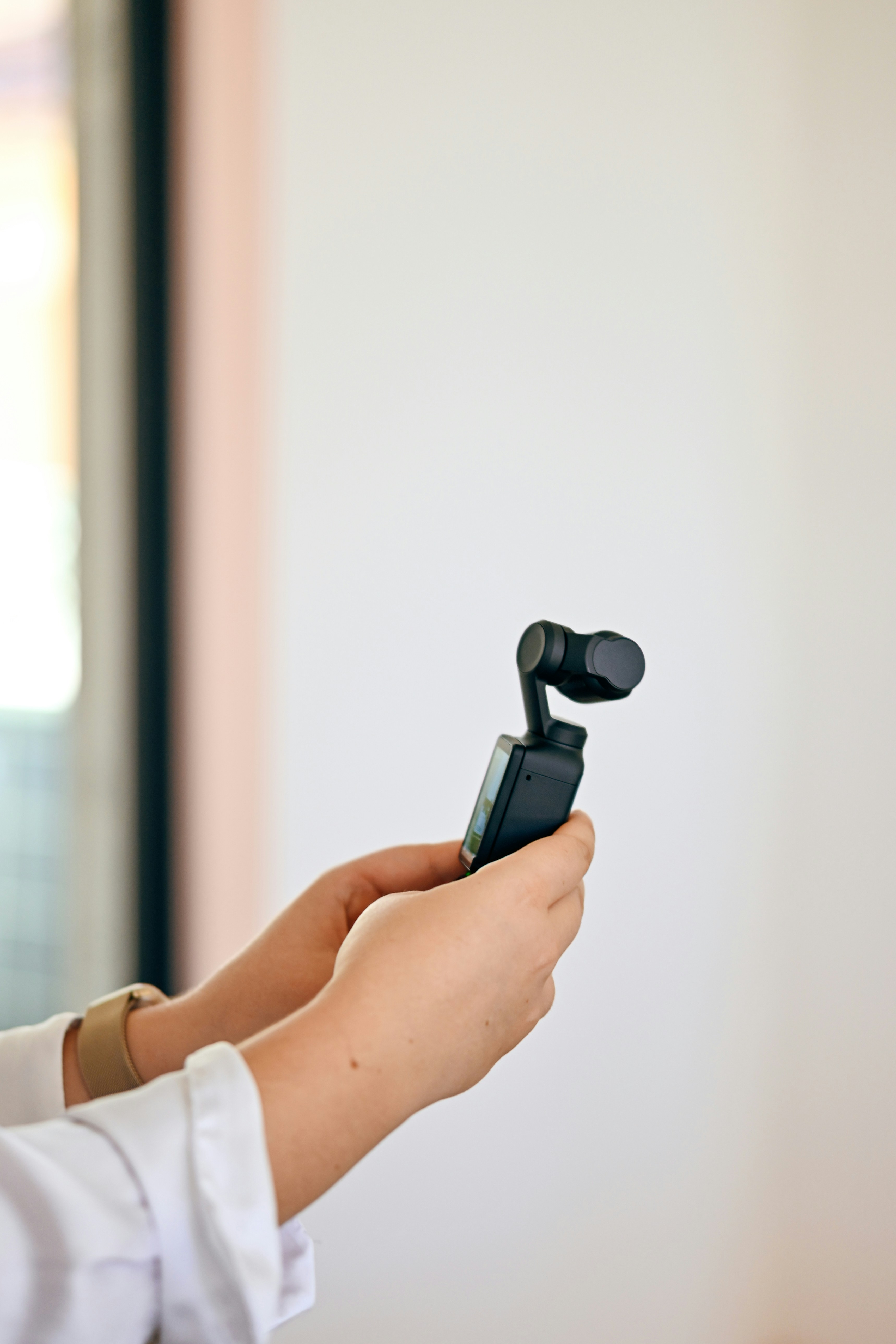 Hands holding a compact black gimbal camera