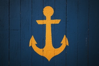 Yellow anchor symbol on a blue wooden background
