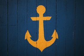 Yellow anchor symbol on a blue wooden background