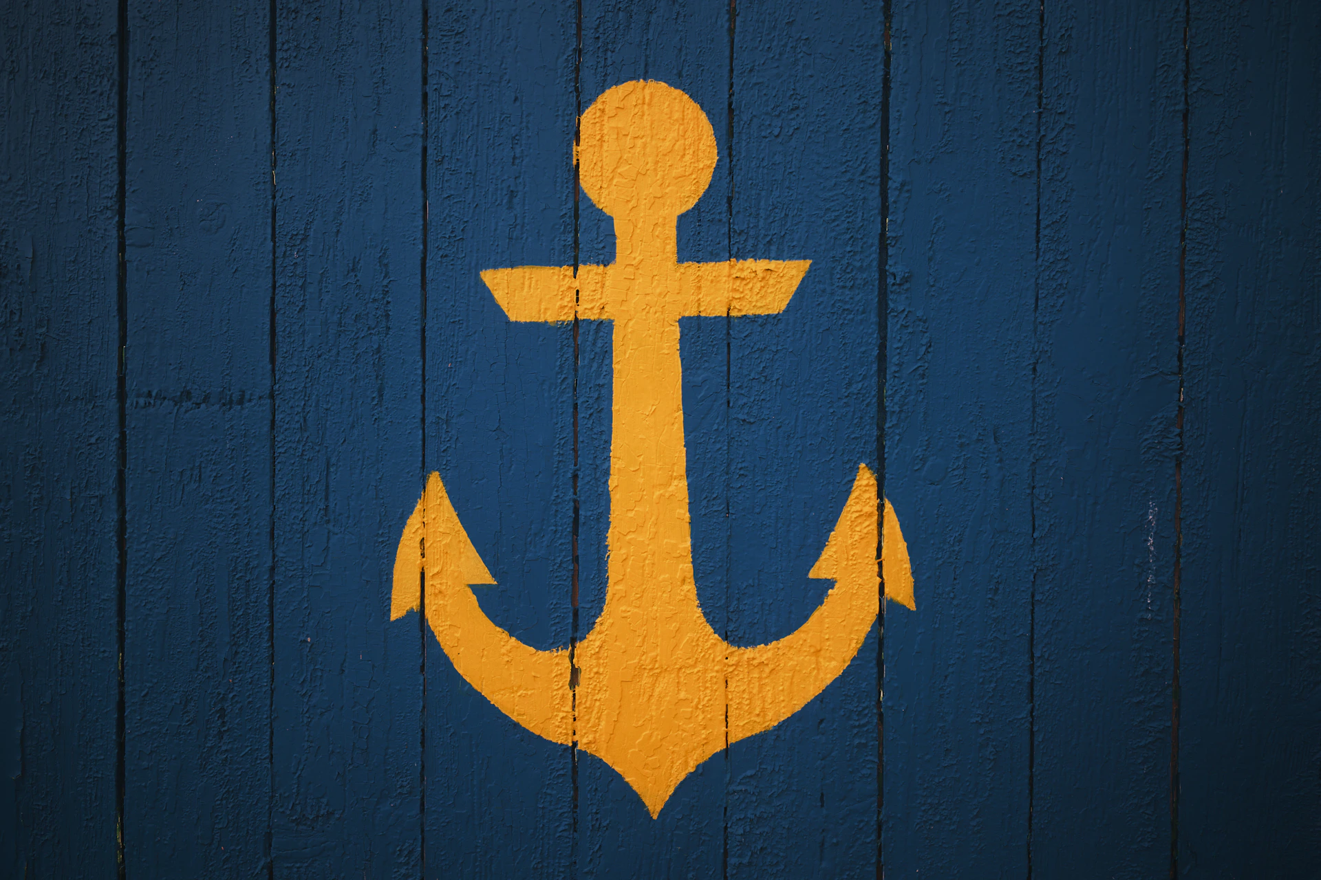 Yellow anchor symbol on a blue wooden background