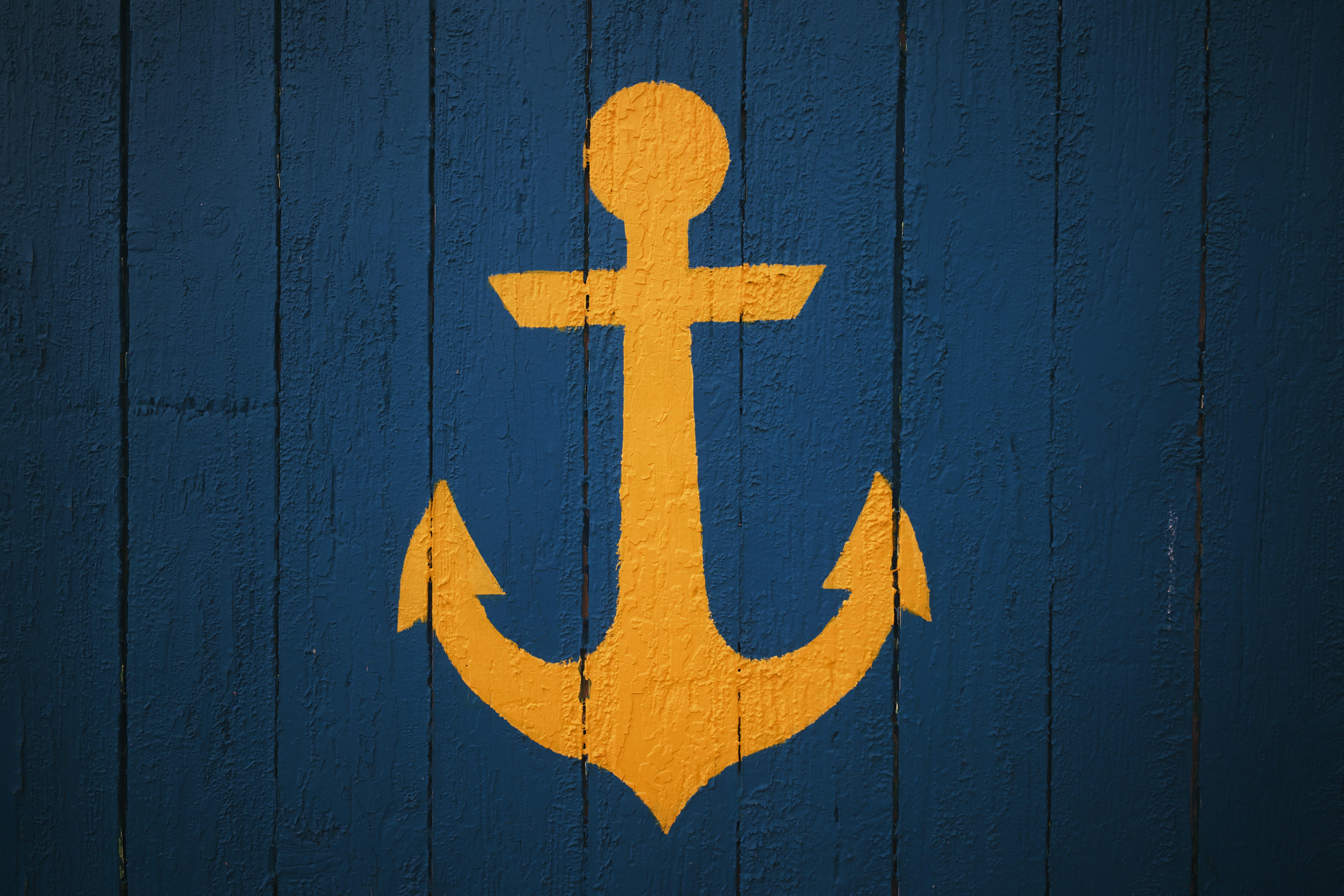 Yellow anchor symbol on a blue wooden background