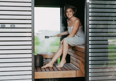 Woman in sauna pouring water on hot stones