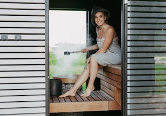 Woman in sauna pouring water on hot stones