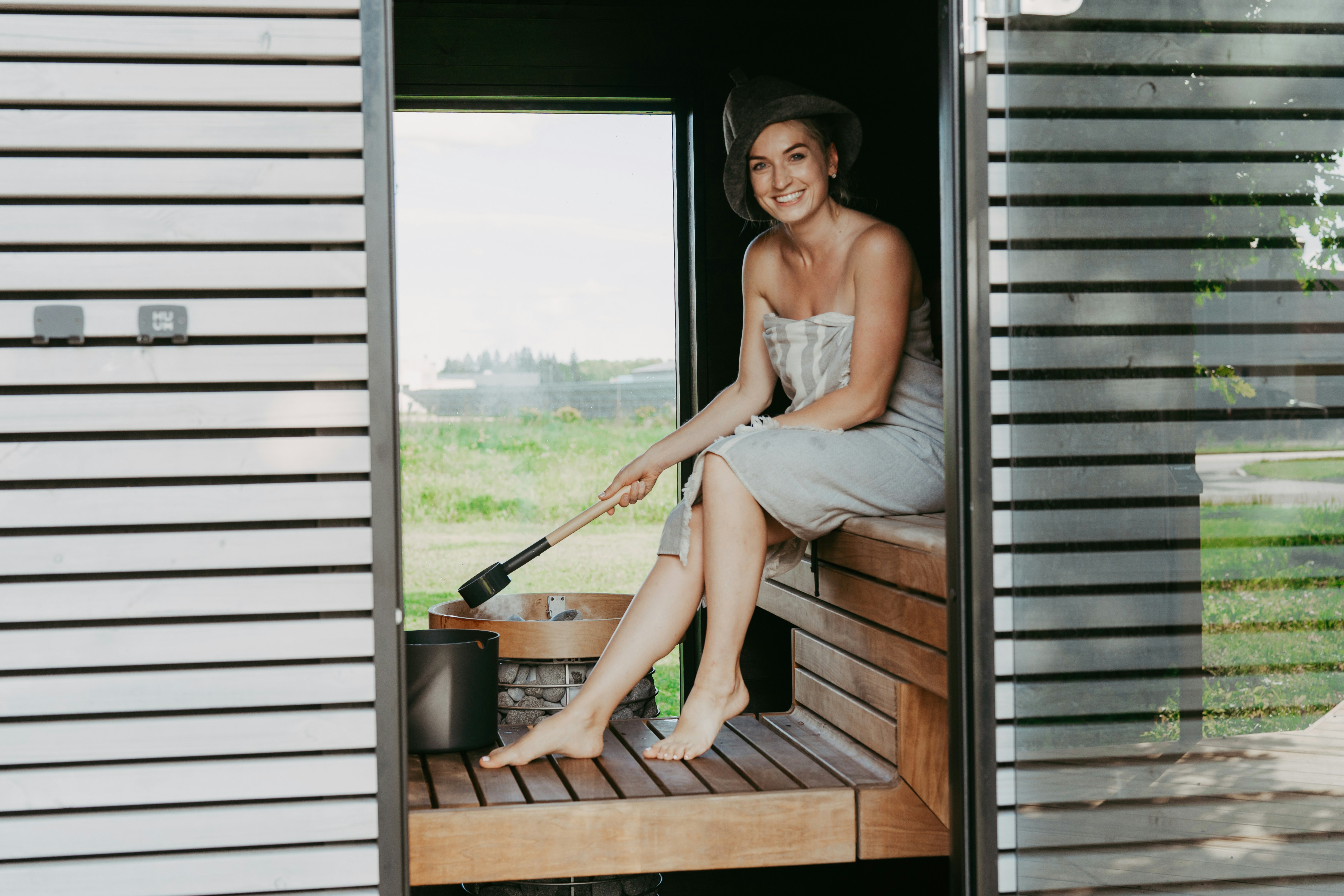 Woman in sauna holding ladle over bucket