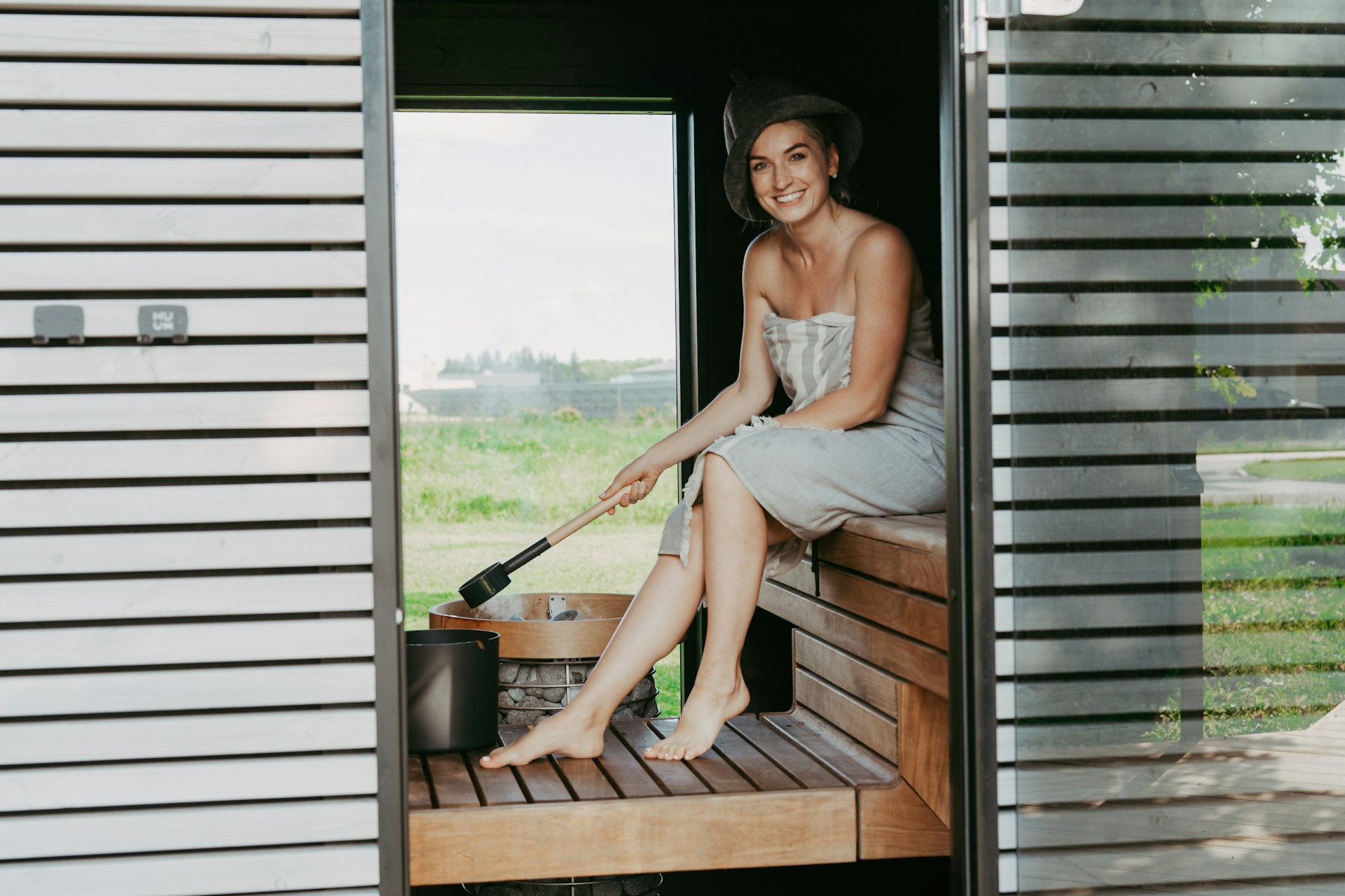 Woman in sauna holding ladle over bucket
