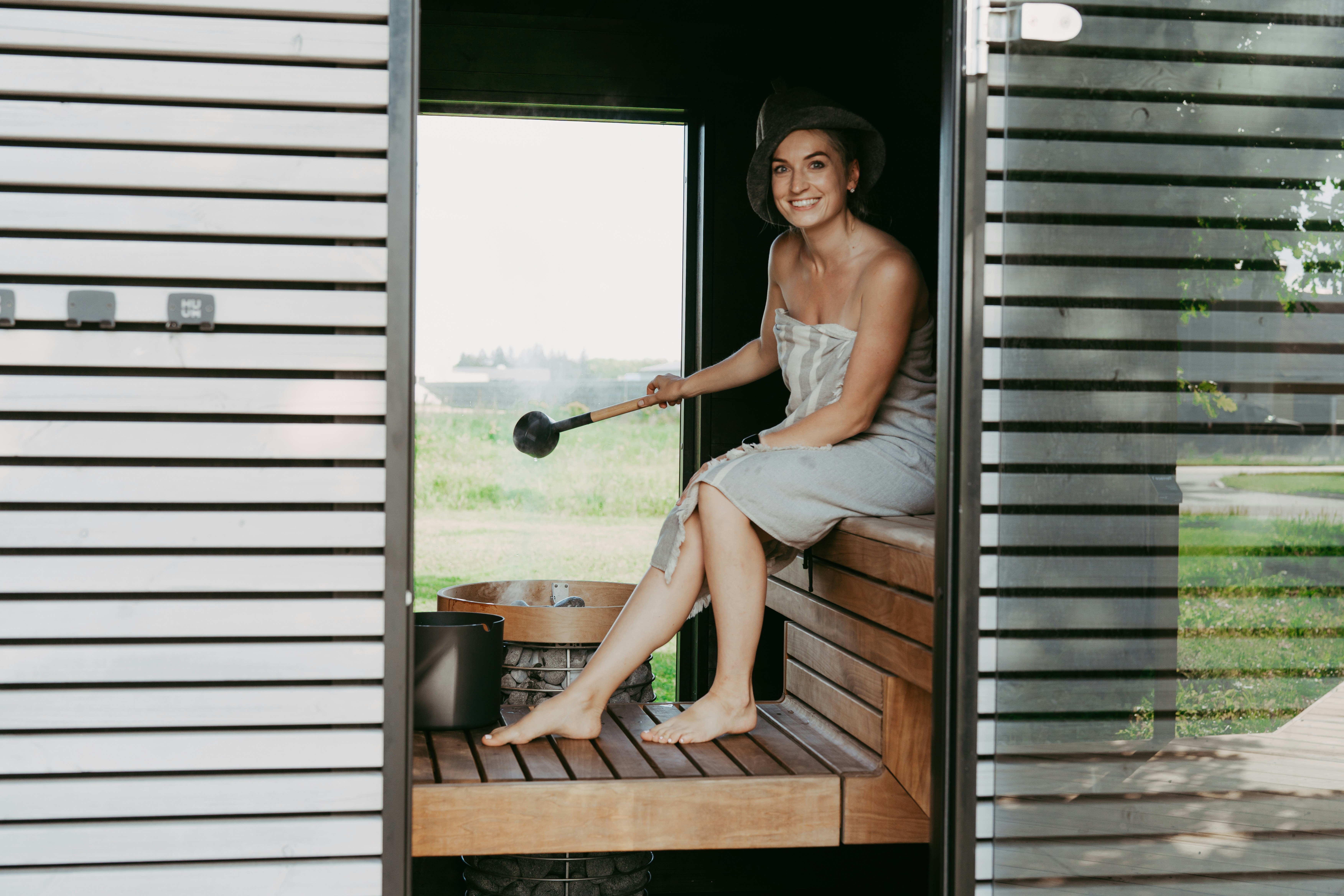 Woman smiling in a wooden sauna with a ladle