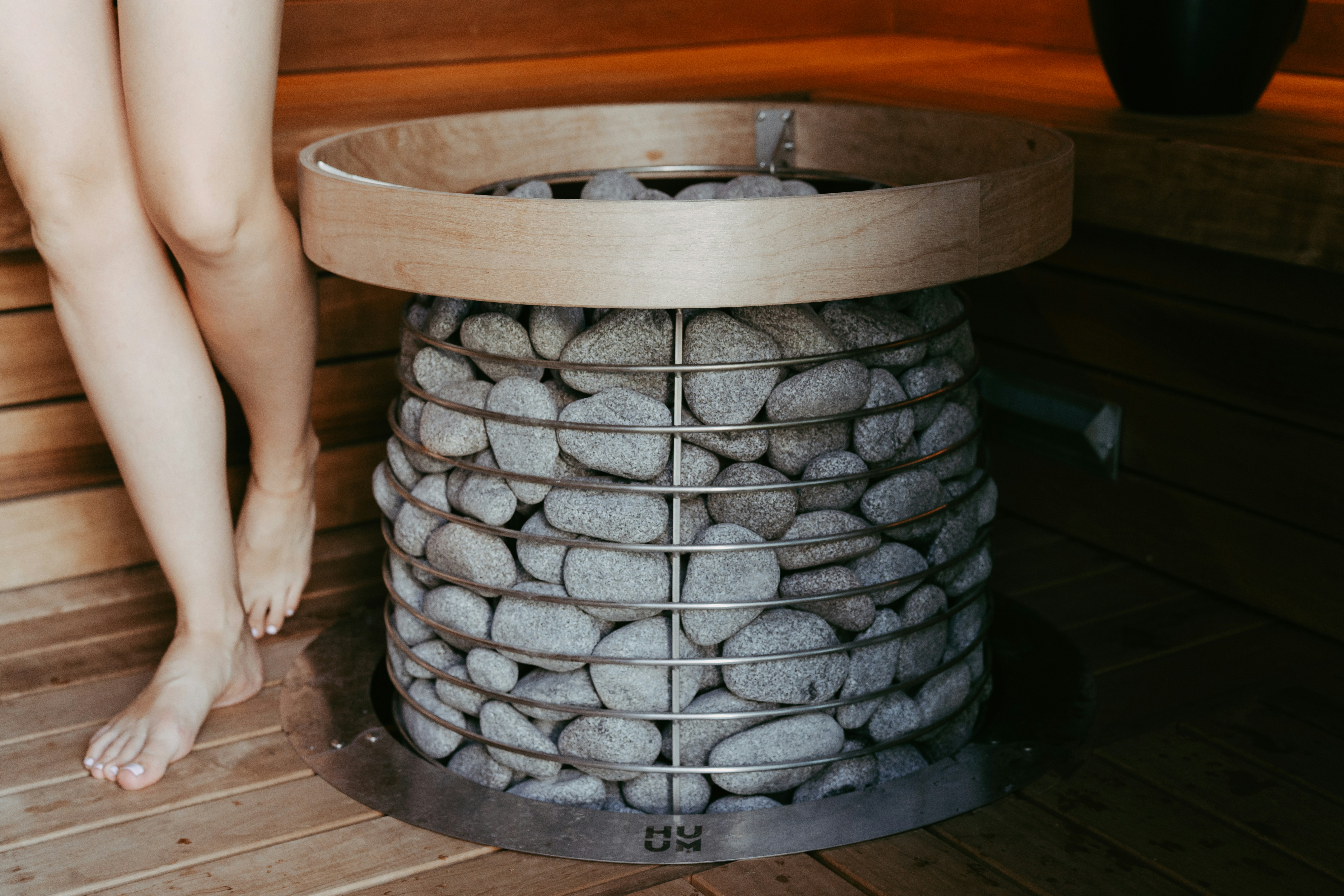 Woman's legs by a sauna heater with hot stones