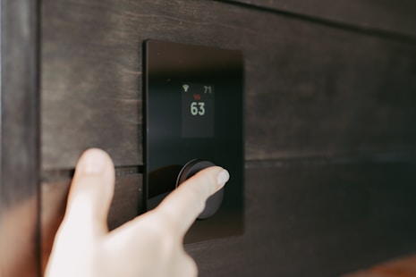 Hand stellt ein digitales Smart-Home-Thermostat ein.