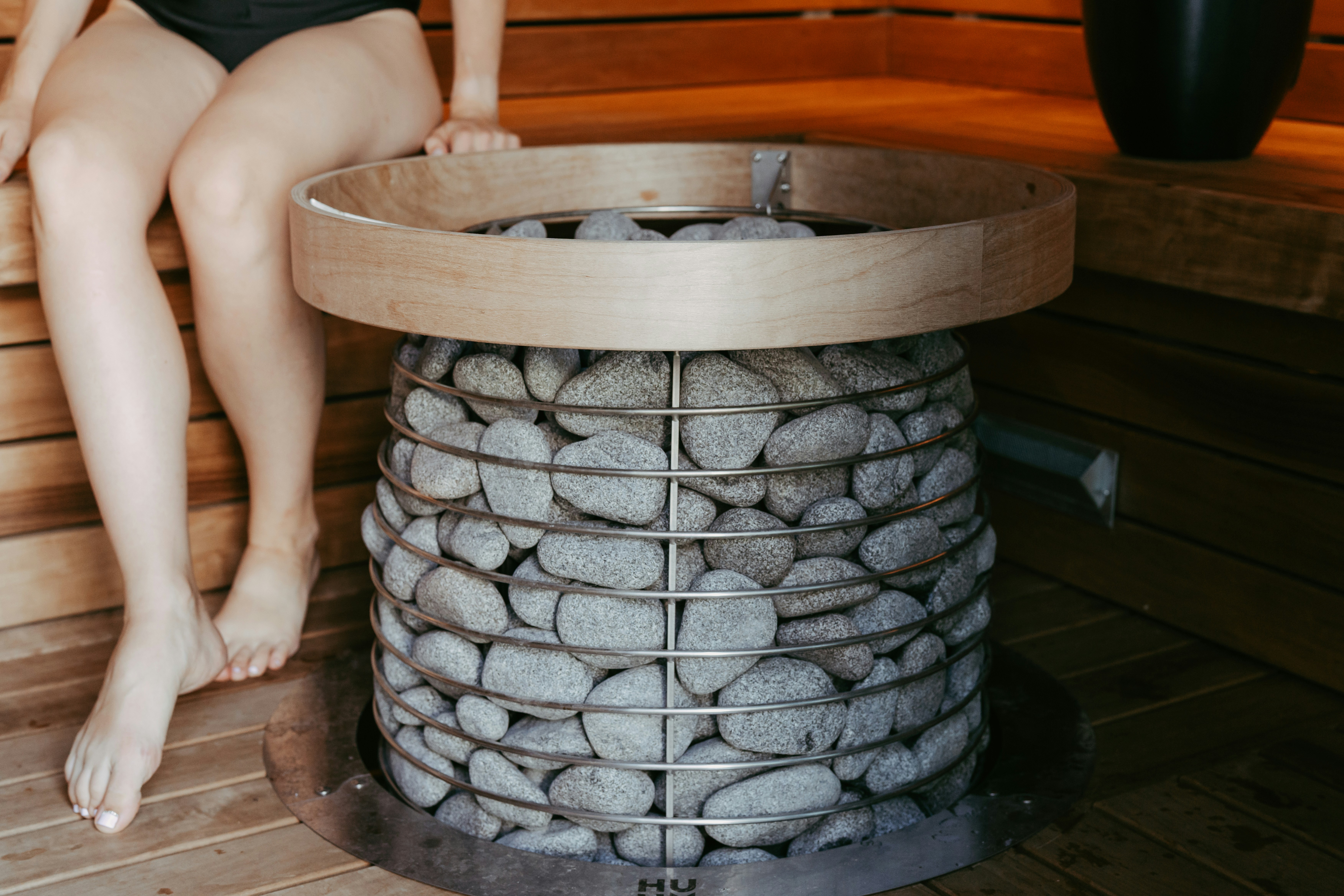 Person sitting in a wooden sauna next to heater