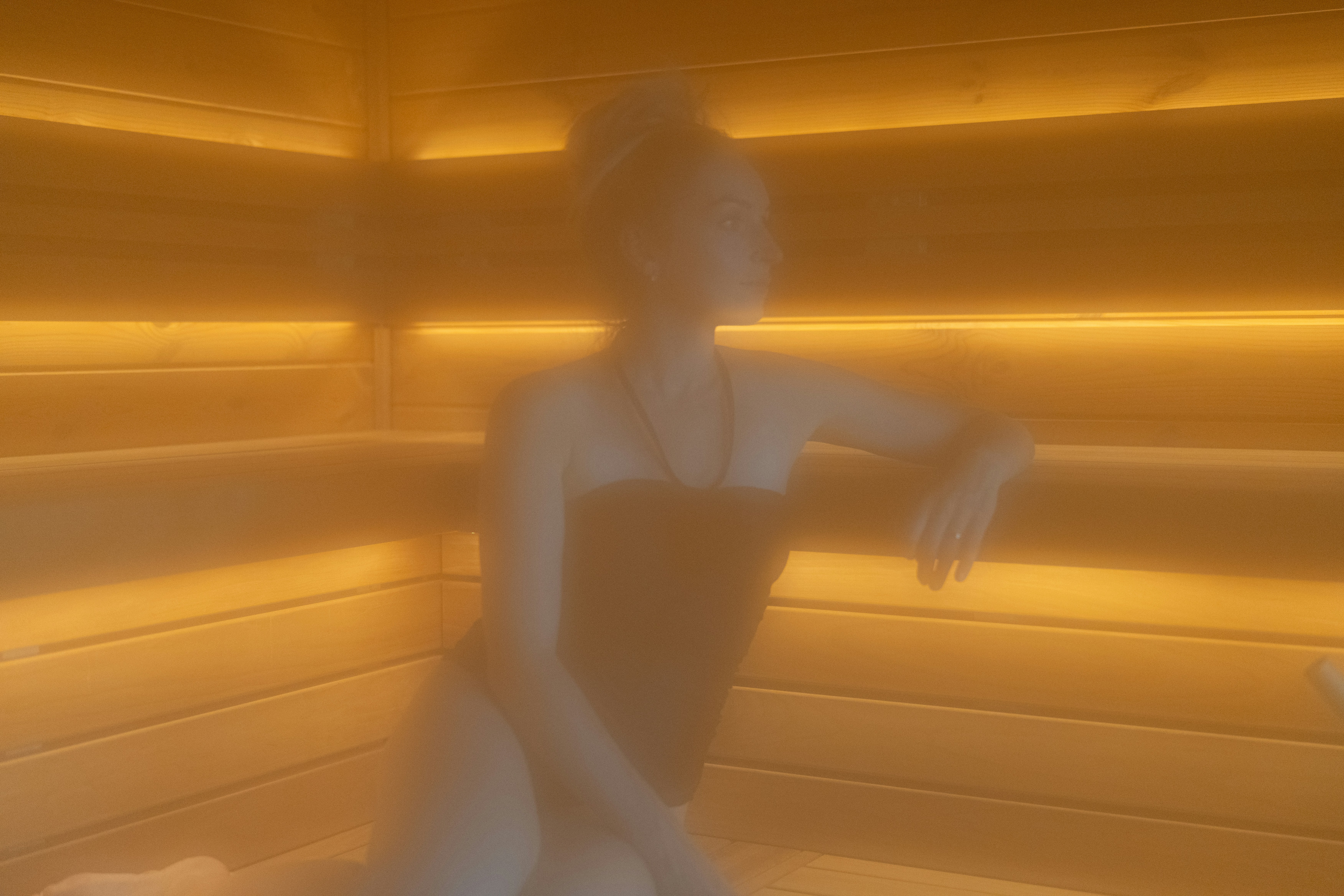 Woman relaxing in a steamy, wood-paneled sauna