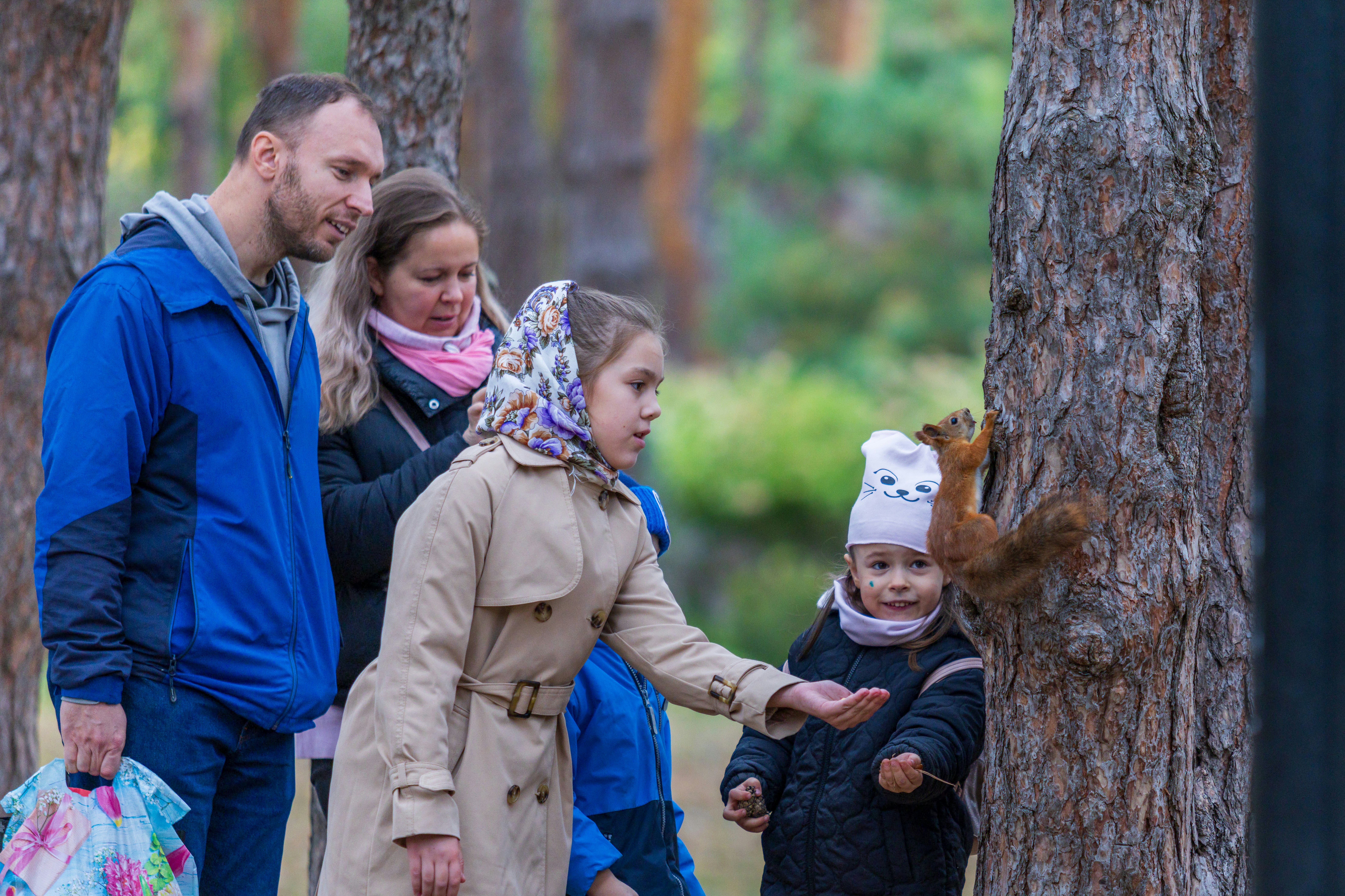 Family feeding a squirrel in a forest