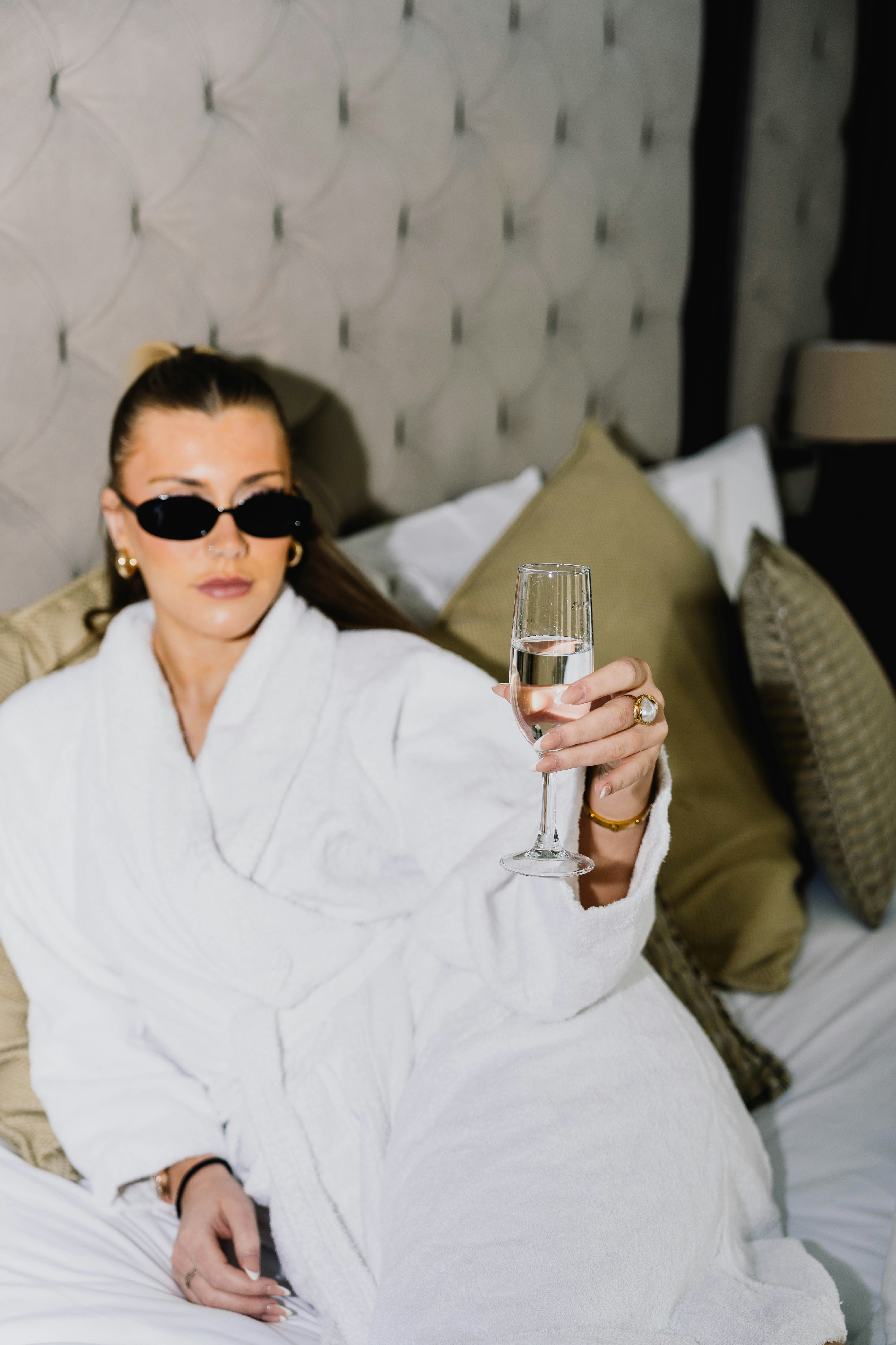 Woman in bathrobe and sunglasses holding champagne