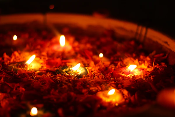 Small candles burning among colourful flower petals