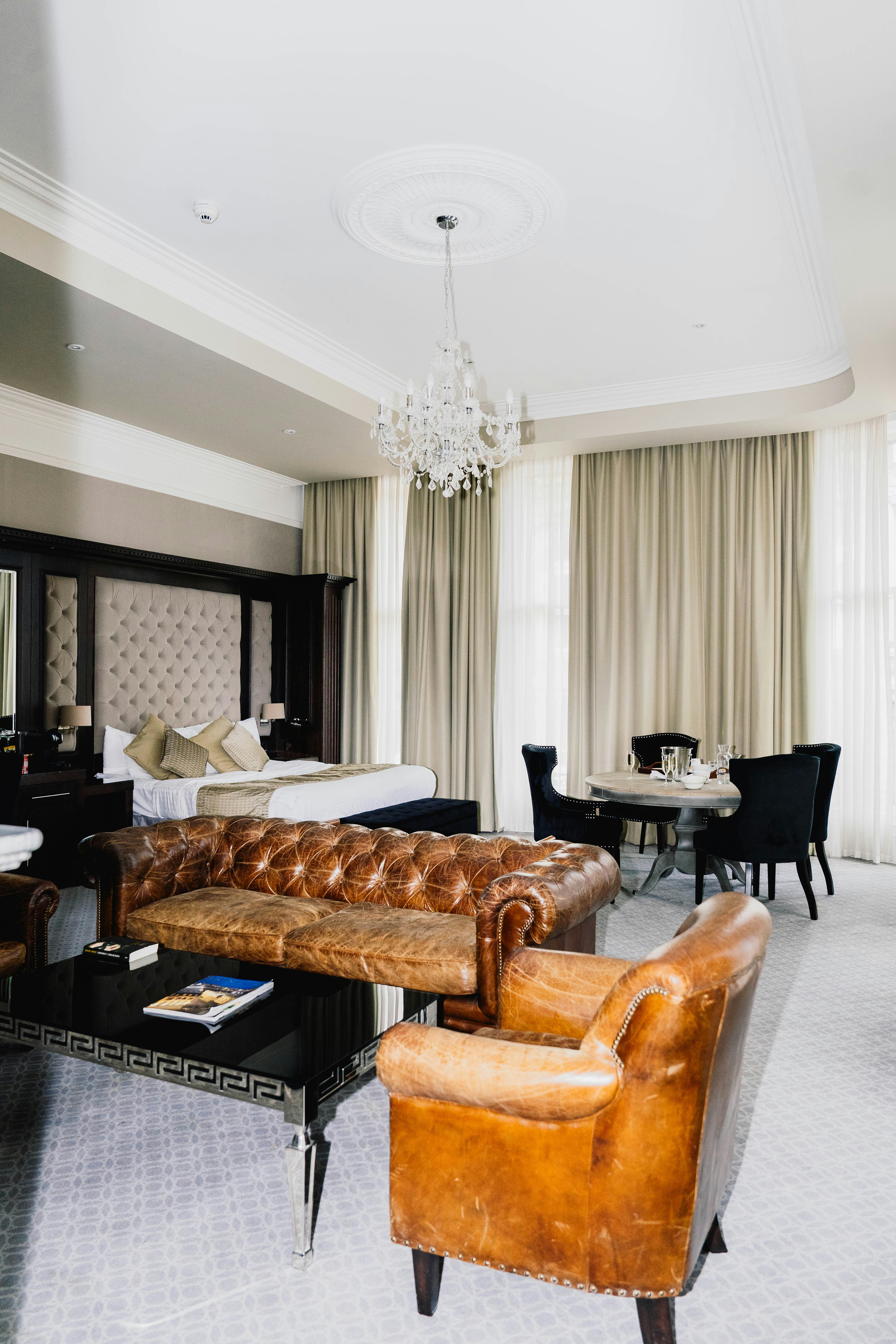 Luxurious hotel suite with vintage leather furniture and chandelier.