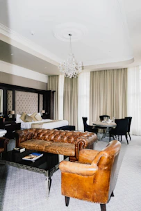 Luxurious hotel suite with vintage leather furniture and chandelier.