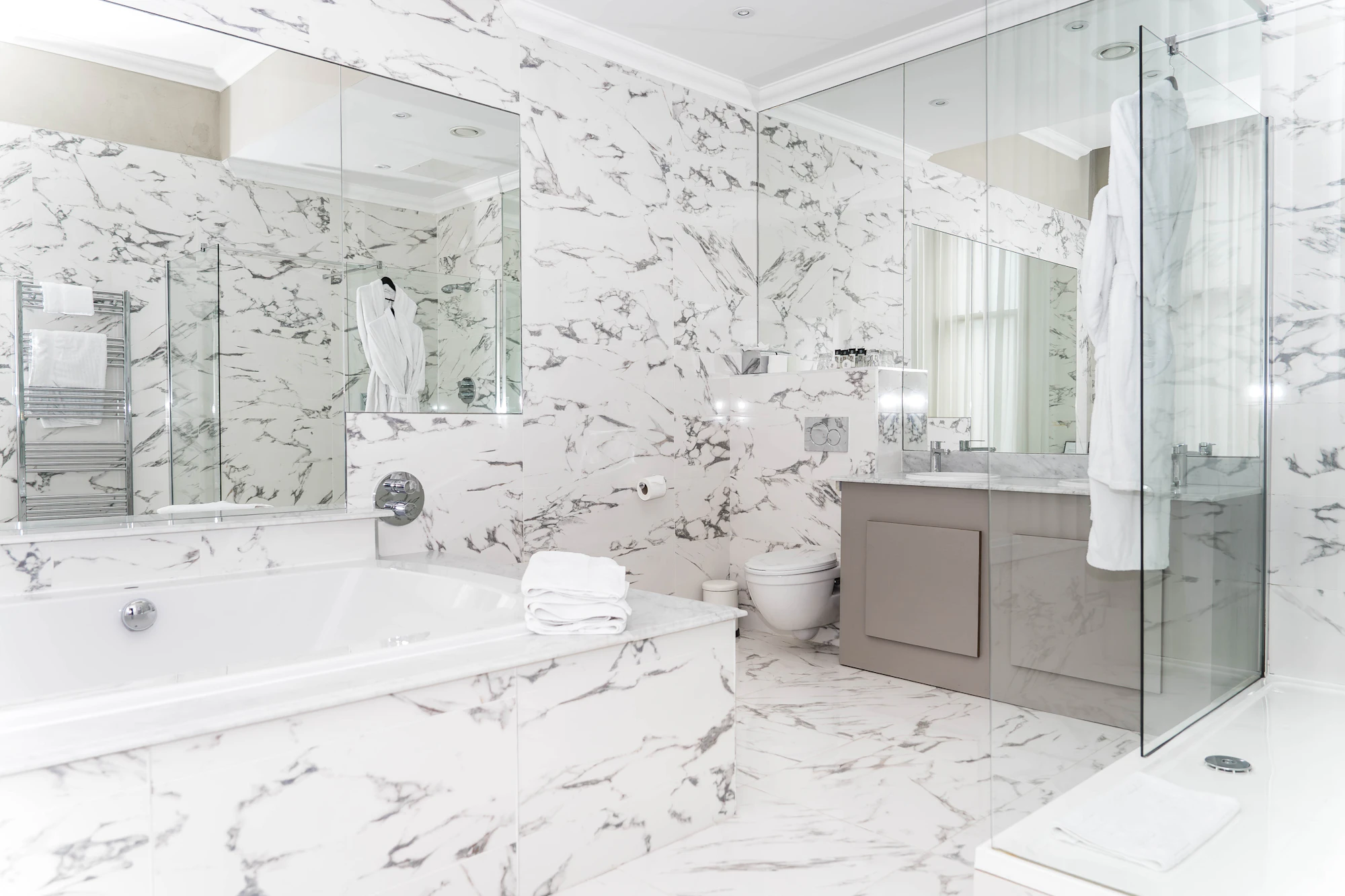 A luxe marble bathroom with sculptural stone surfaces, laid by hand