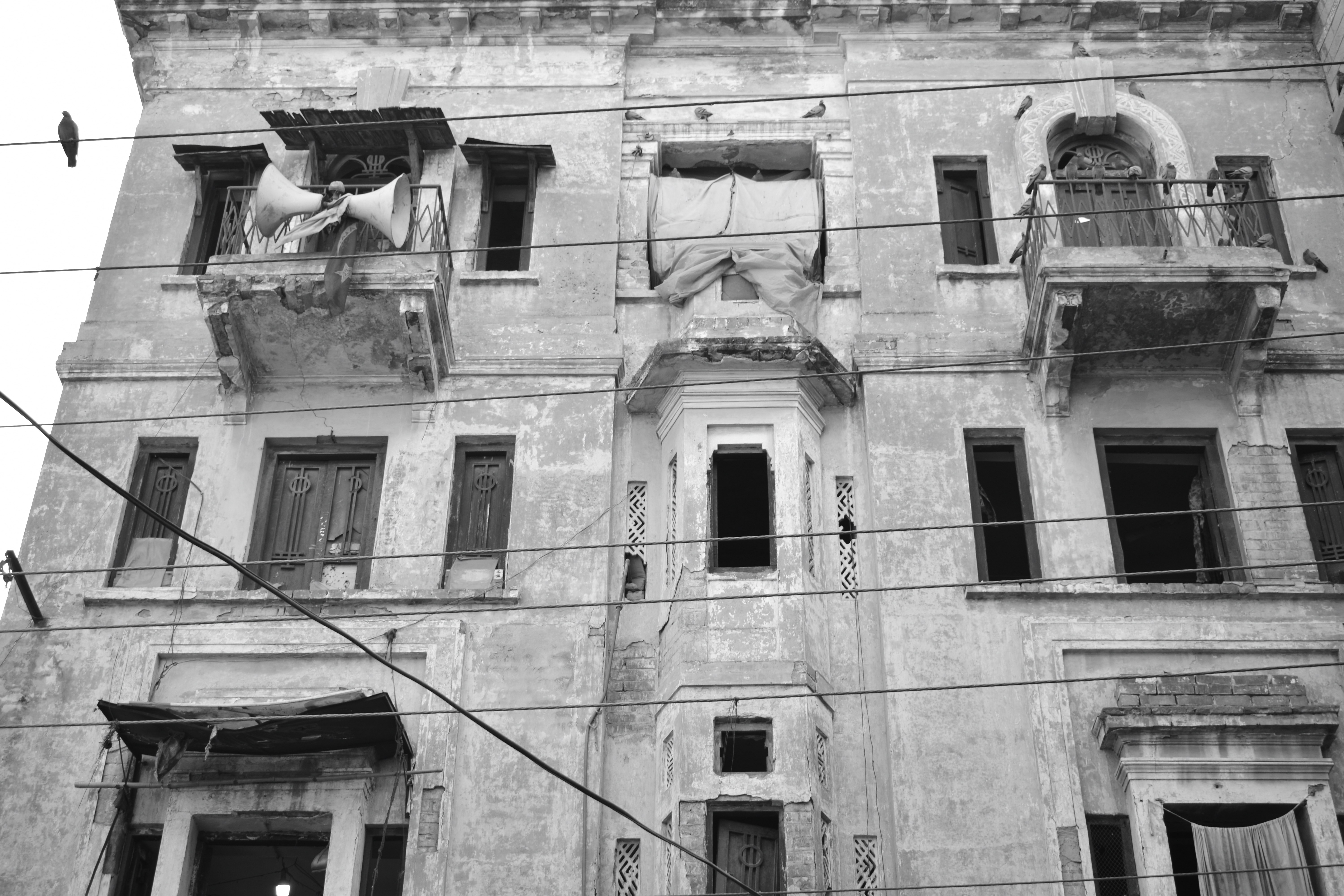 Façade de bâtiment délabrée avec fenêtres et balcons cassés.