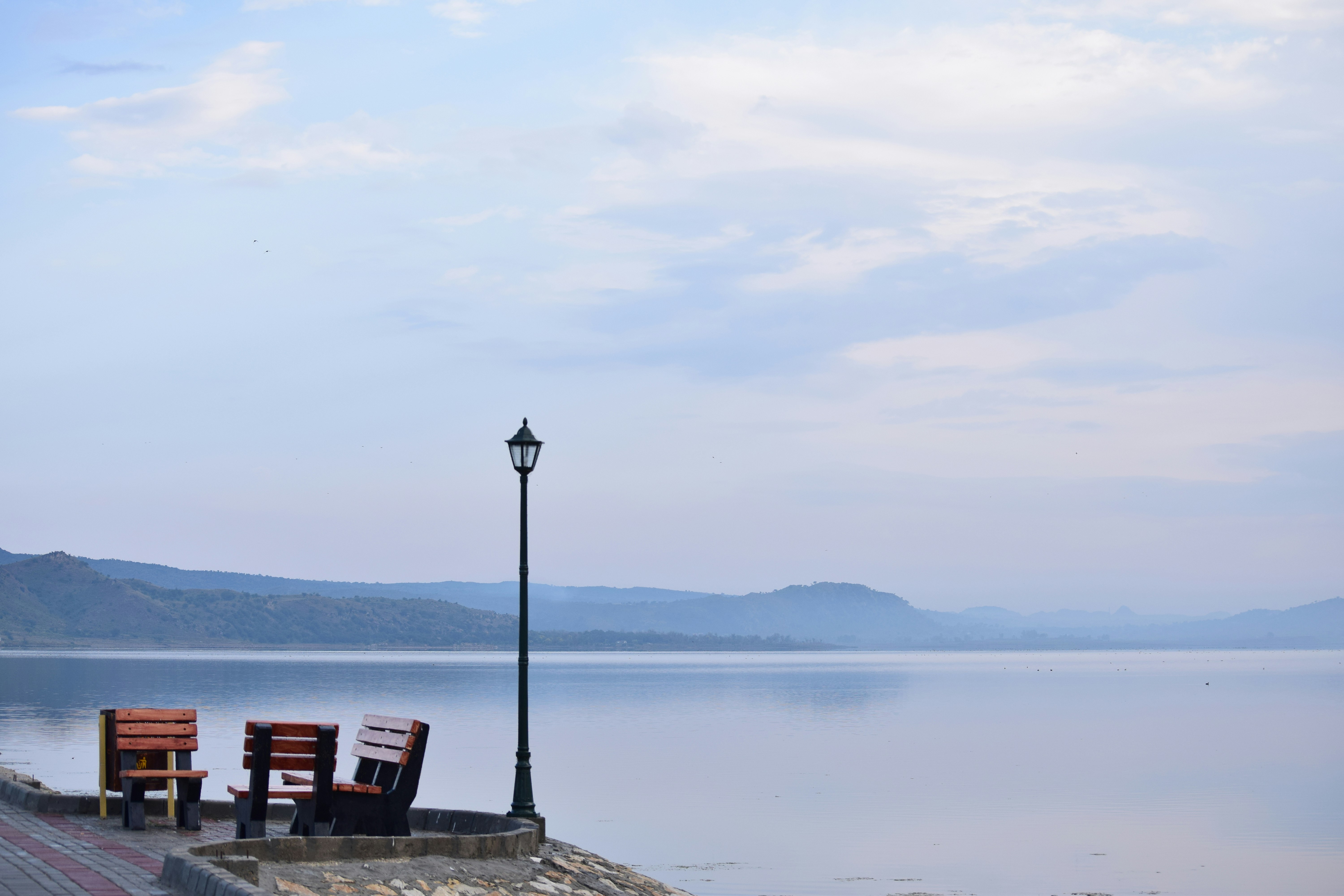 Two benches and a lamp post by a calm lake.