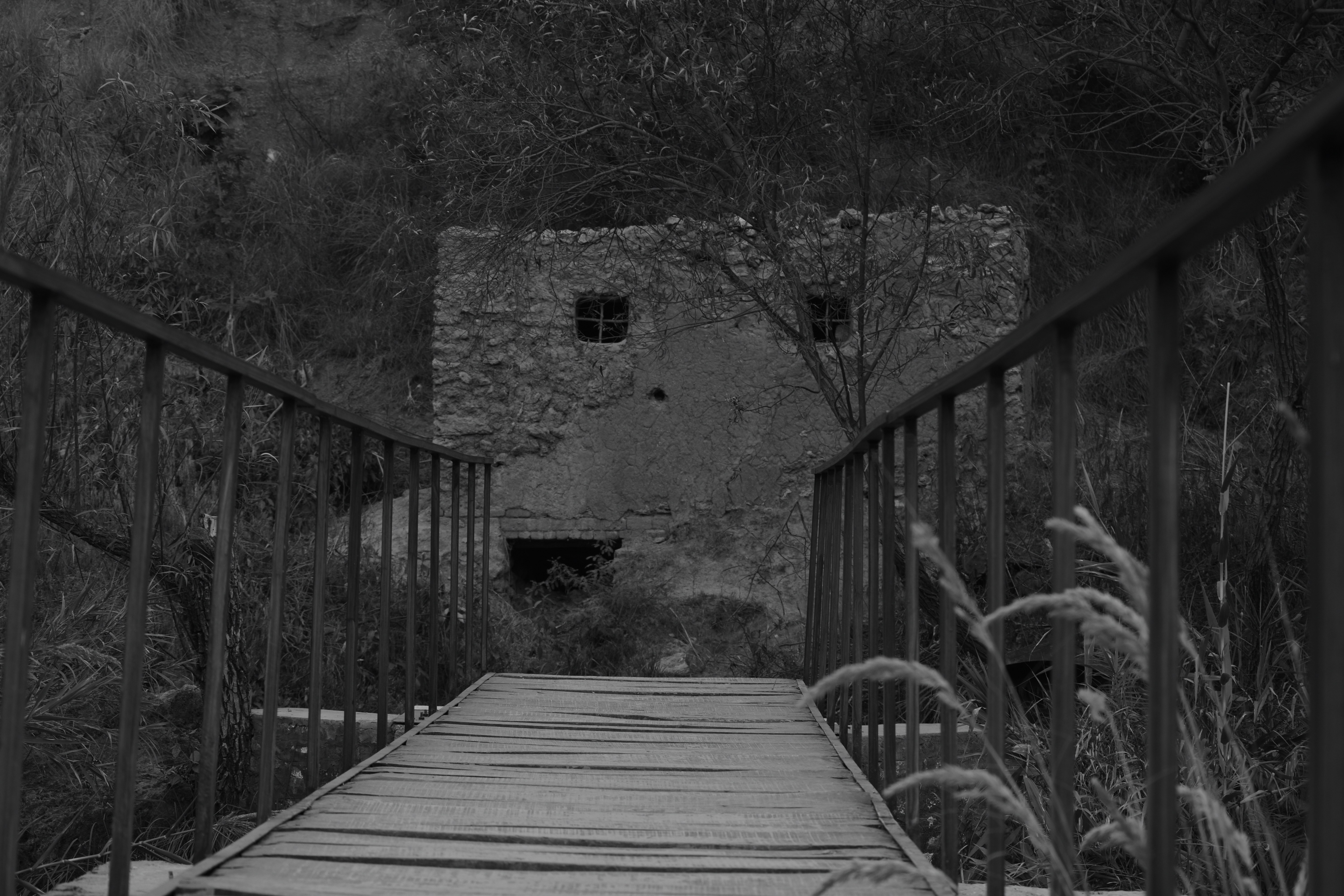 Wooden bridge leads to an old stone building.