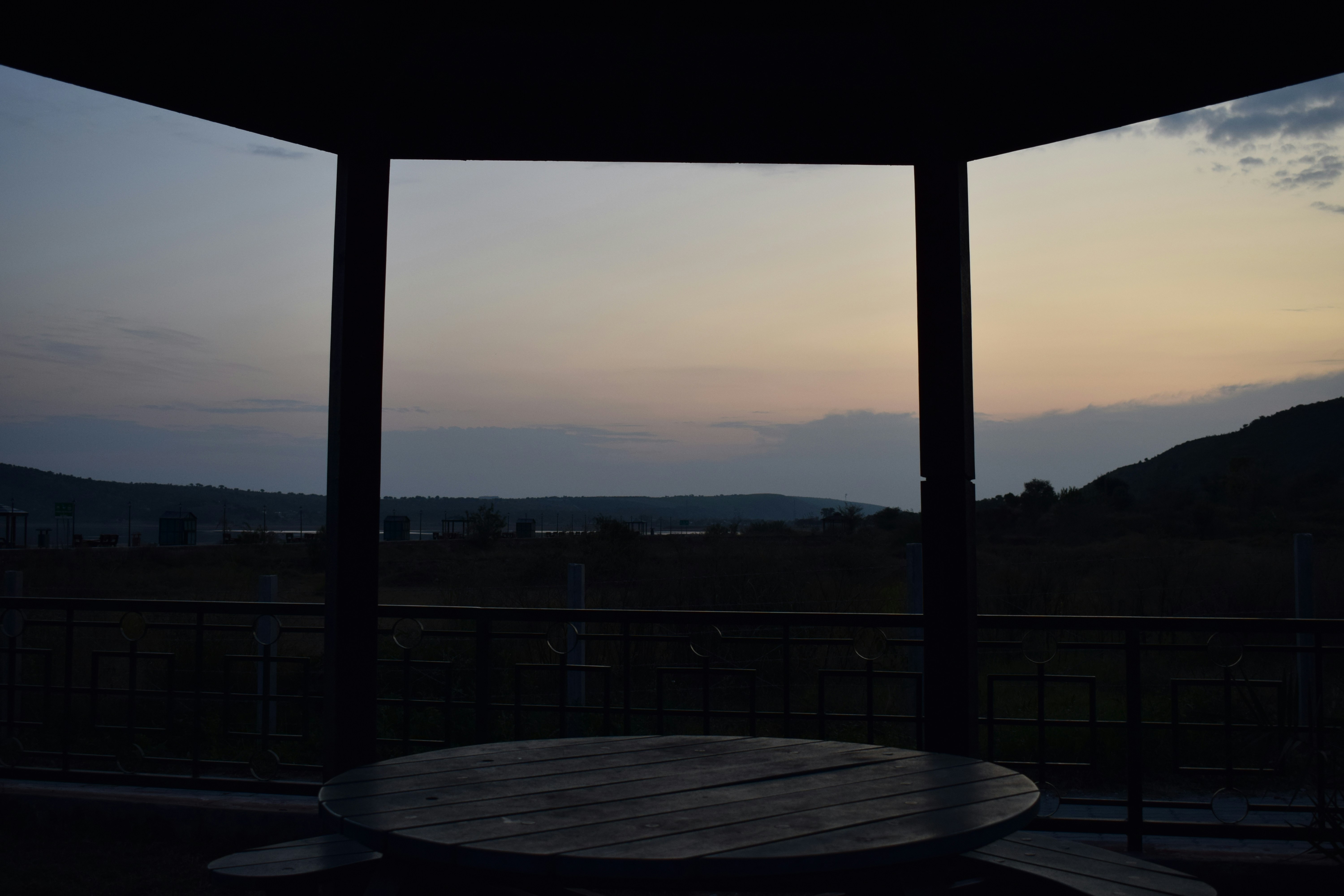 View of sunset from a dark wooden gazebo.