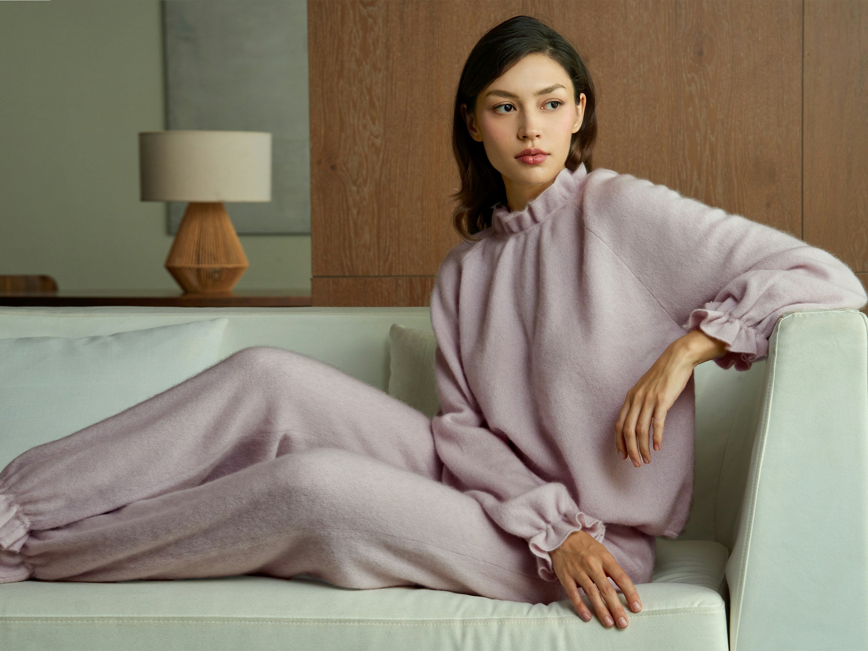 Woman in light purple pajamas relaxing on sofa.