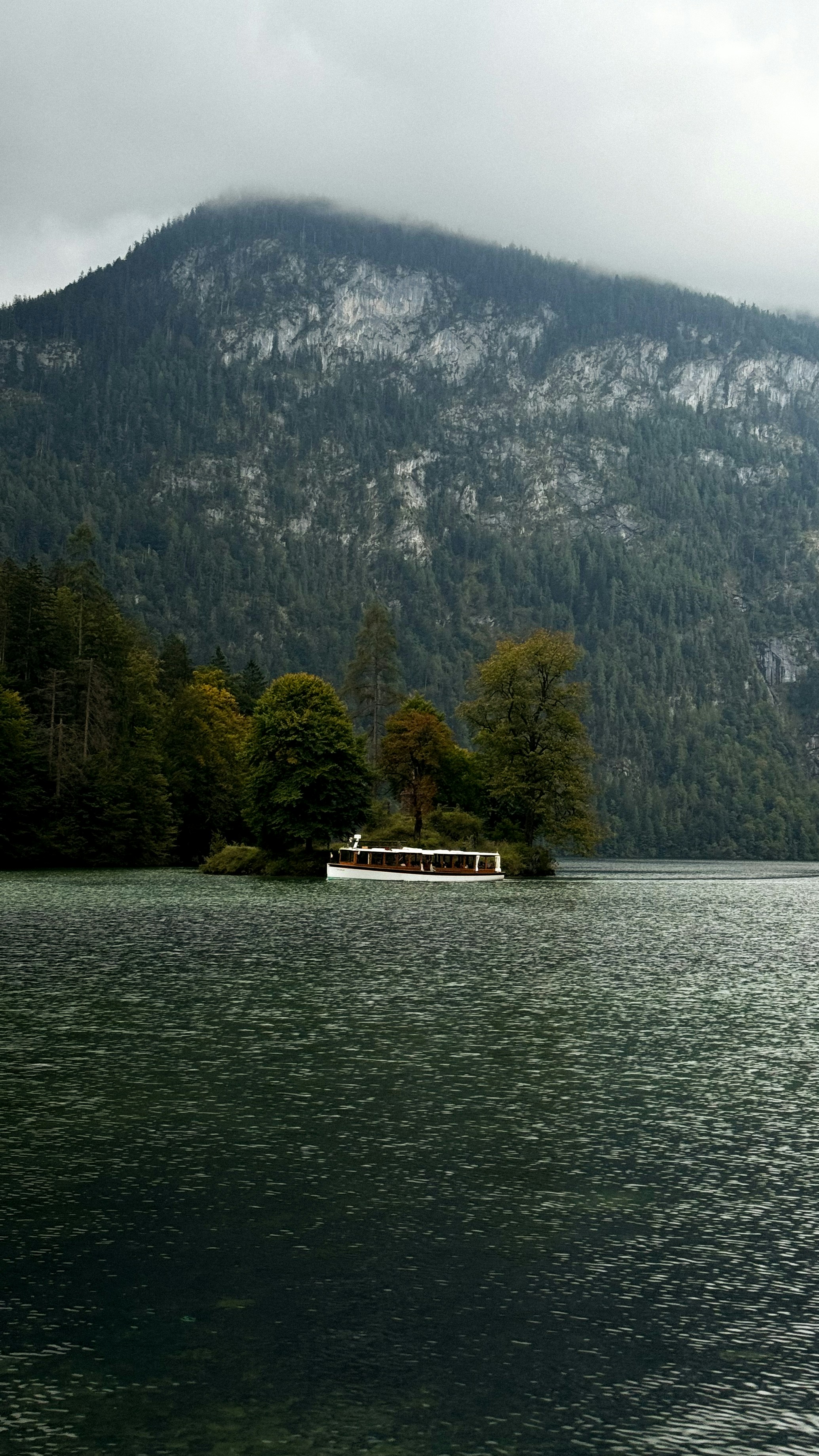 Ein Boot auf einem See in der Nähe eines bewaldeten Berges.