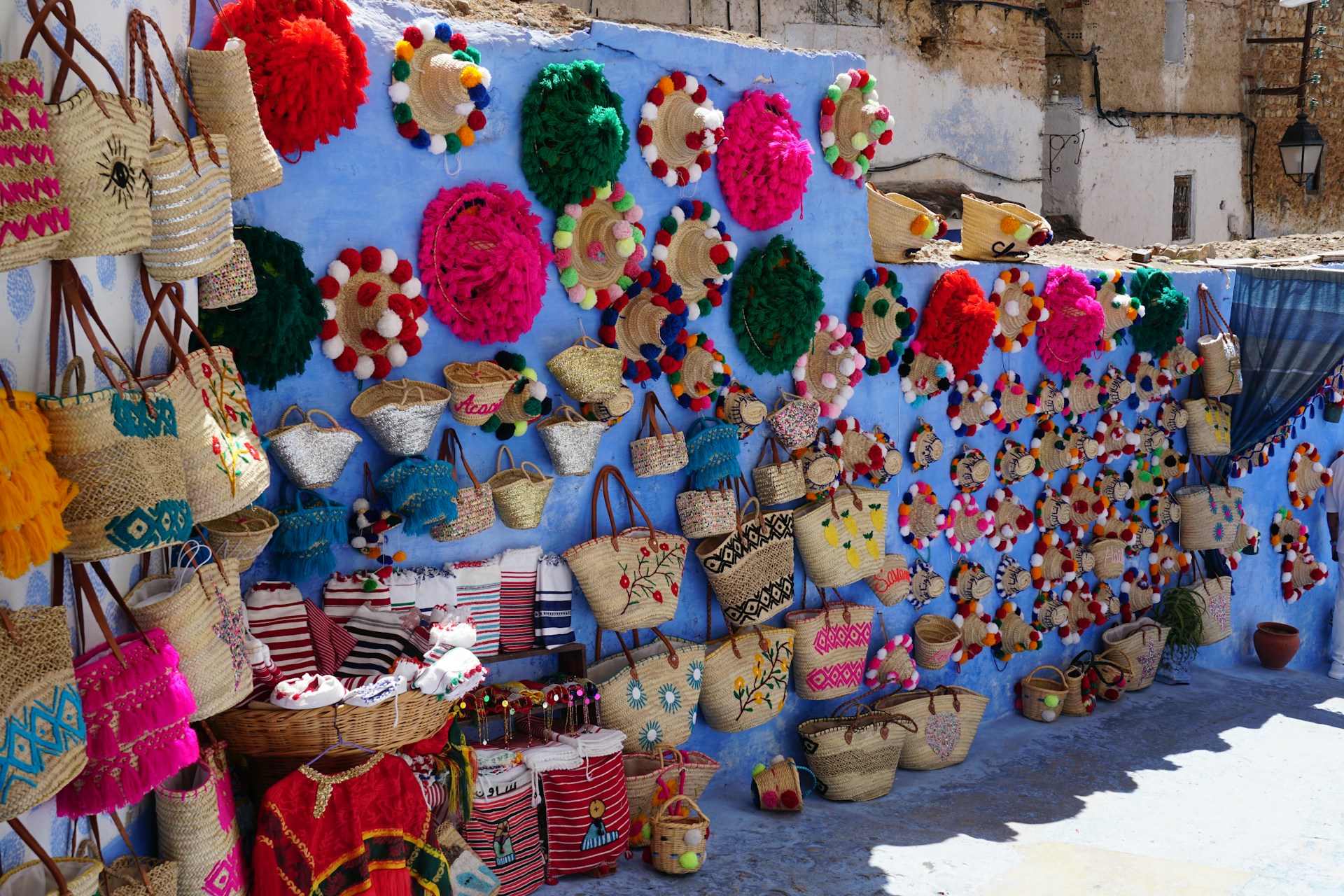 Colorful woven bags and decorations displayed on blue wall.
