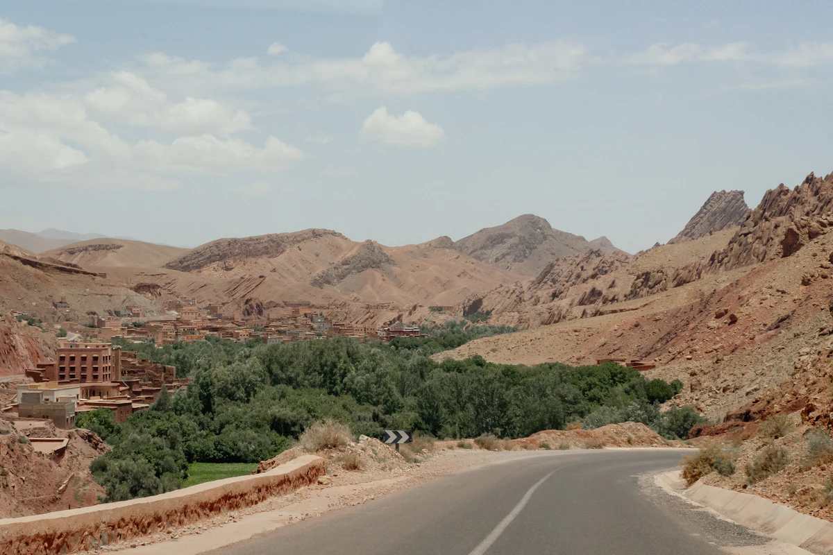 A road into the green valley at Boumalne Dadès, with bare mountains and a village behind