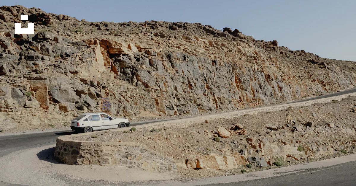 Car Driving Over Rocks White car driving on a winding road through rocky terrain. photo – Free ...