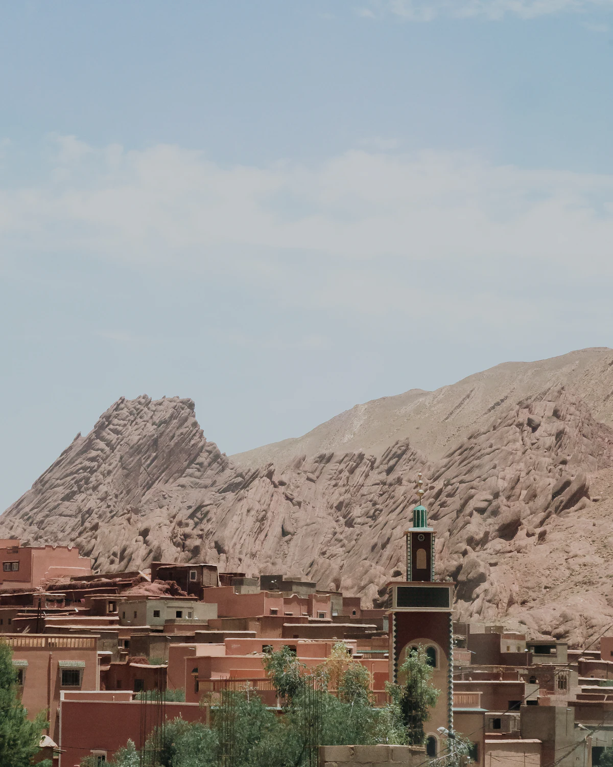 Clay-colored houses and a minaret below a ridge of eroded rock at Boumalne Dadès