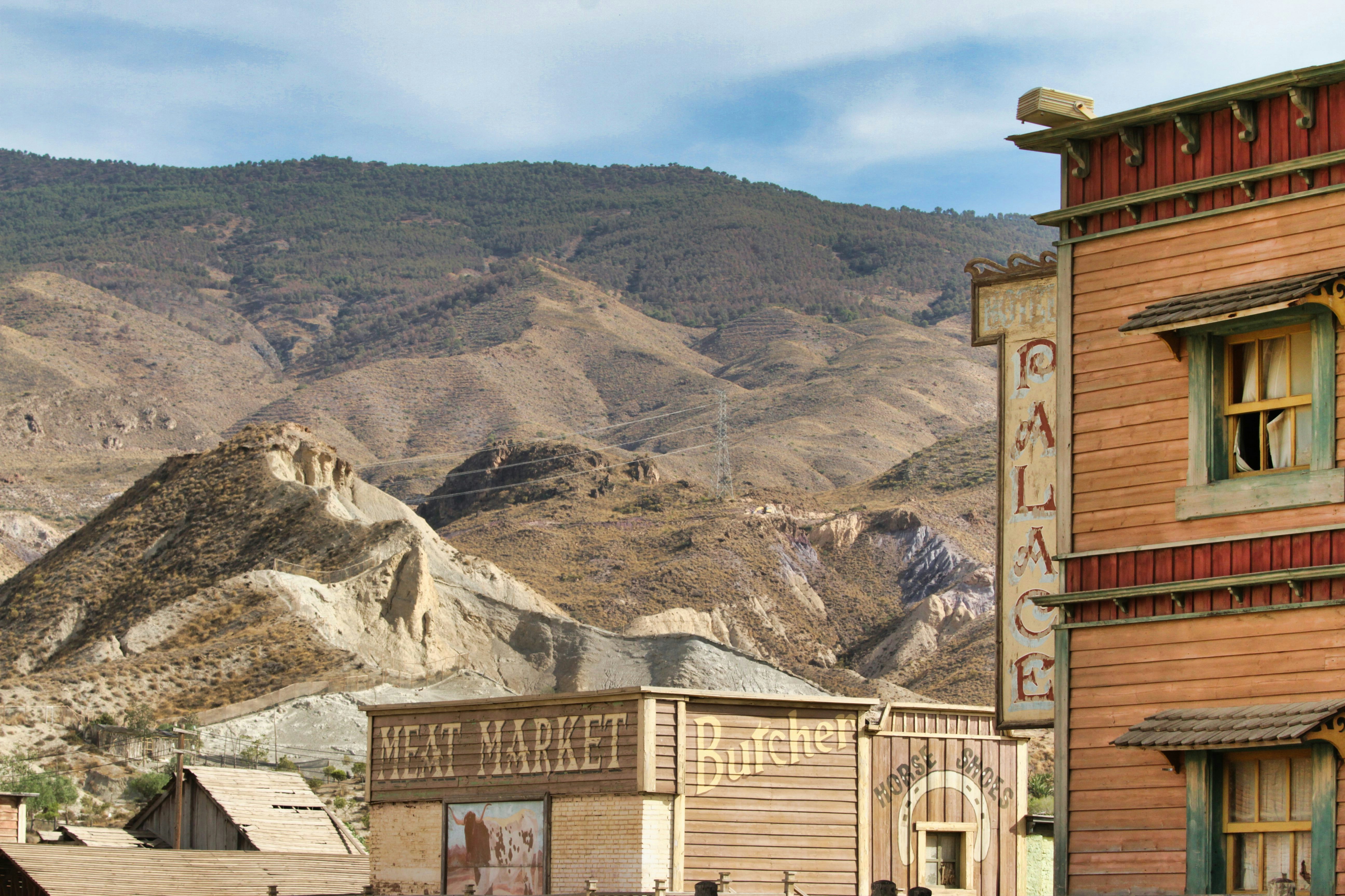 Stop image for Luxury Rockies Passage: Calgary to Kelowna in 3 Days - Old western town buildings with desert mountains background -  in Western Canada - Photo by Marc Snailum on Unsplash