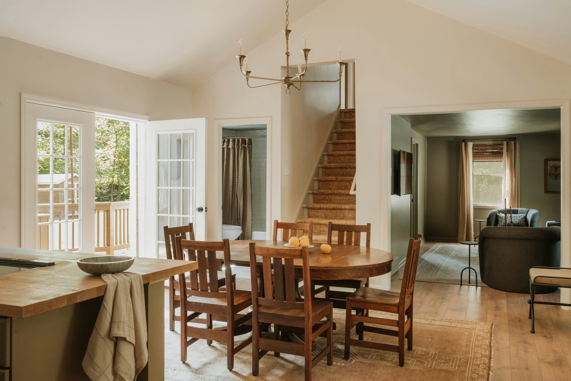 Dining area with wooden table and chairs, stairs nearby.