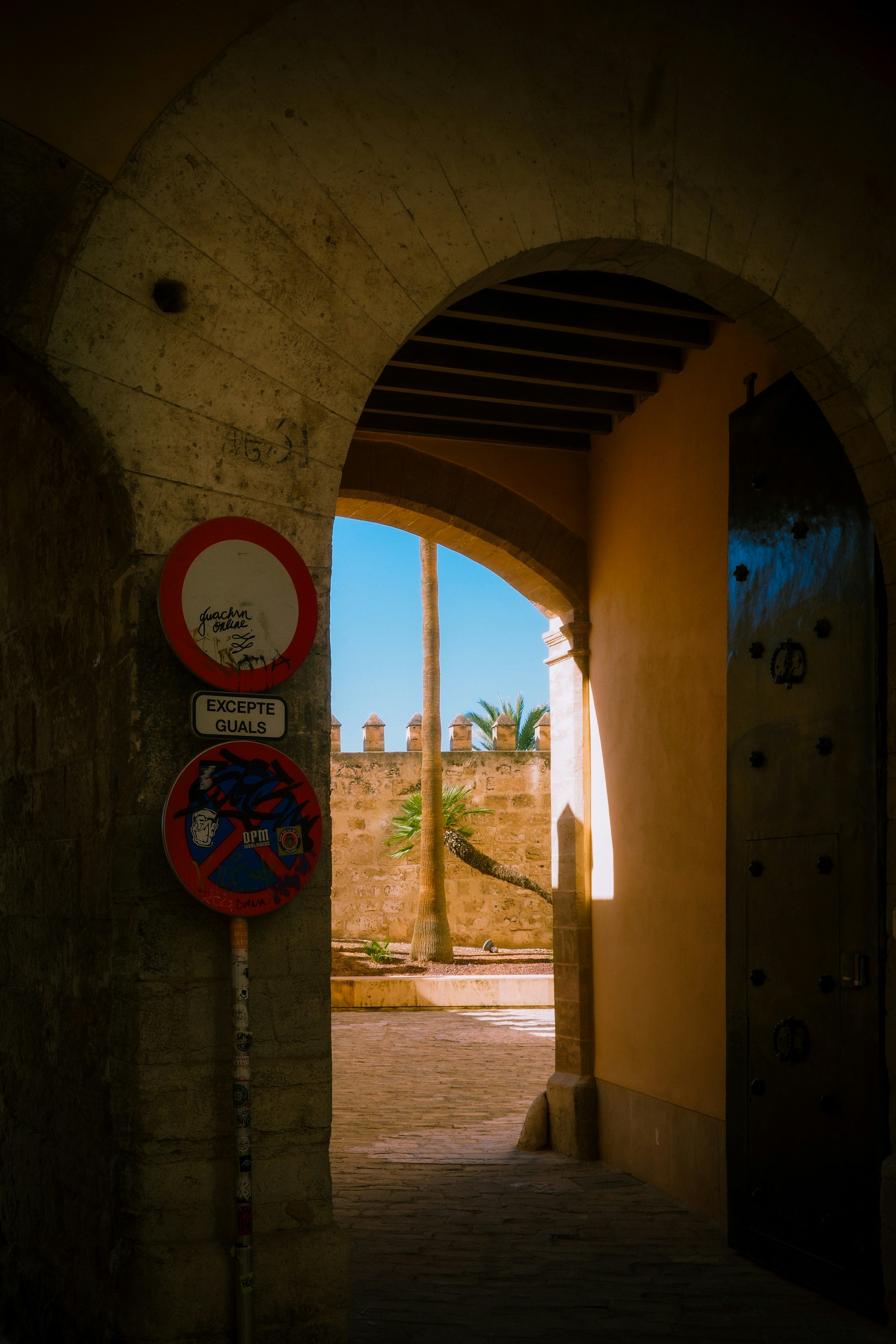 Arched entryway leading to a courtyard with stone walls.