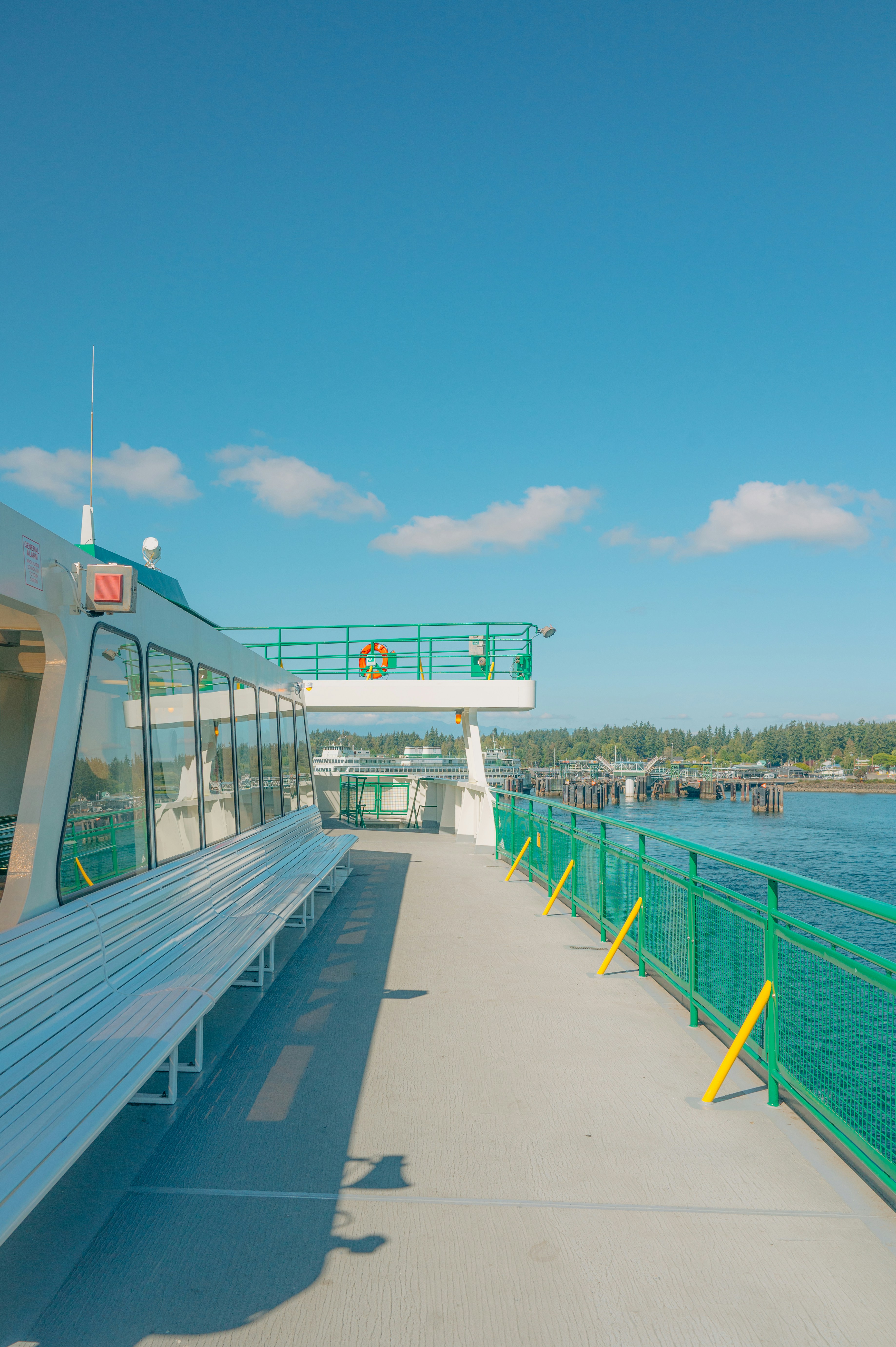 Deck of a ferry with green railings and blue sky