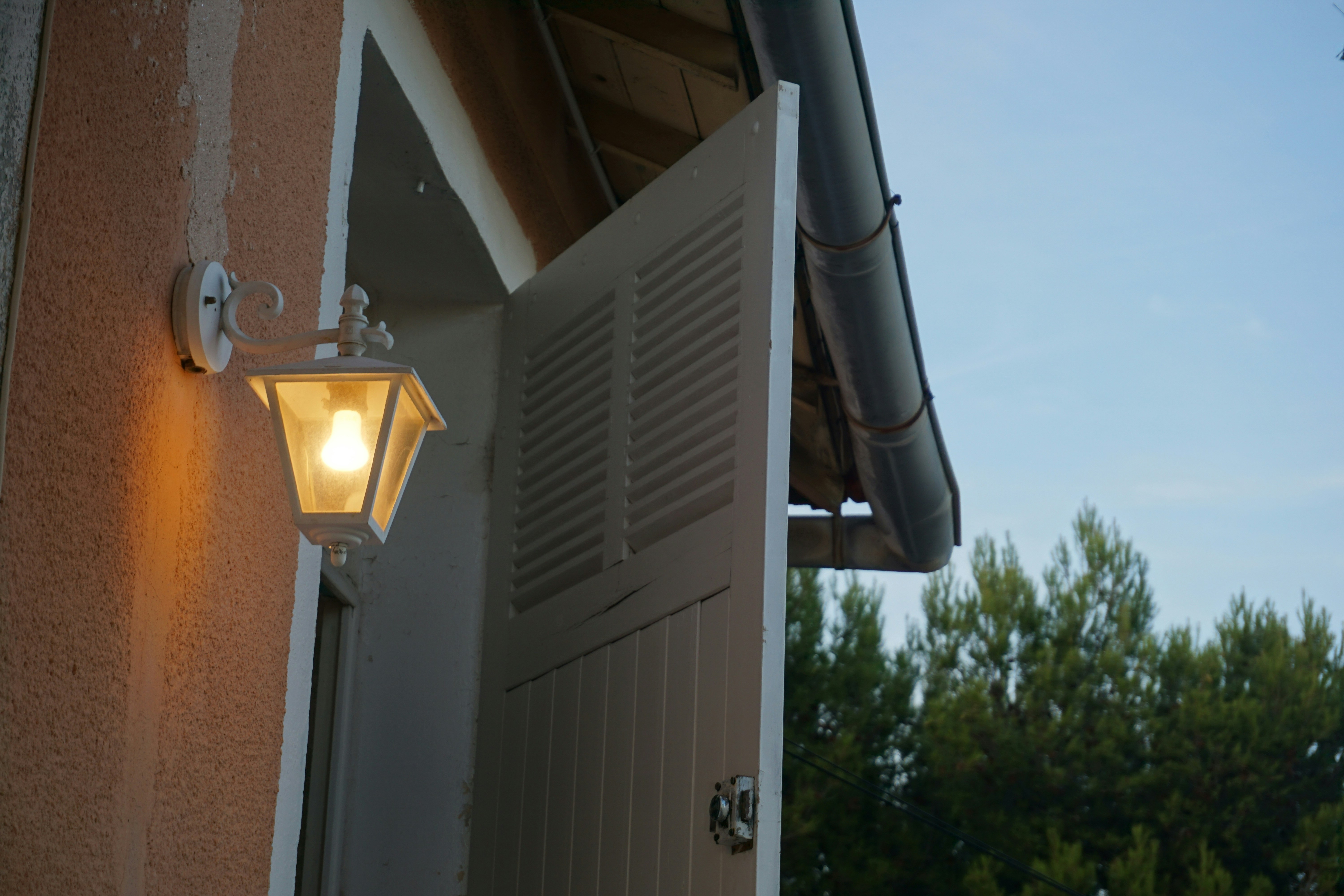 Enerji verimliliğini ve tasarrufunu simgeleyen, üzerinde yeşil yaprak figürü bulunan modern bir LED ampul ve güneş panelli ev konsepti.