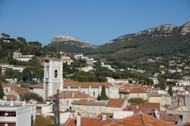 Town with church steeple below forested mountains