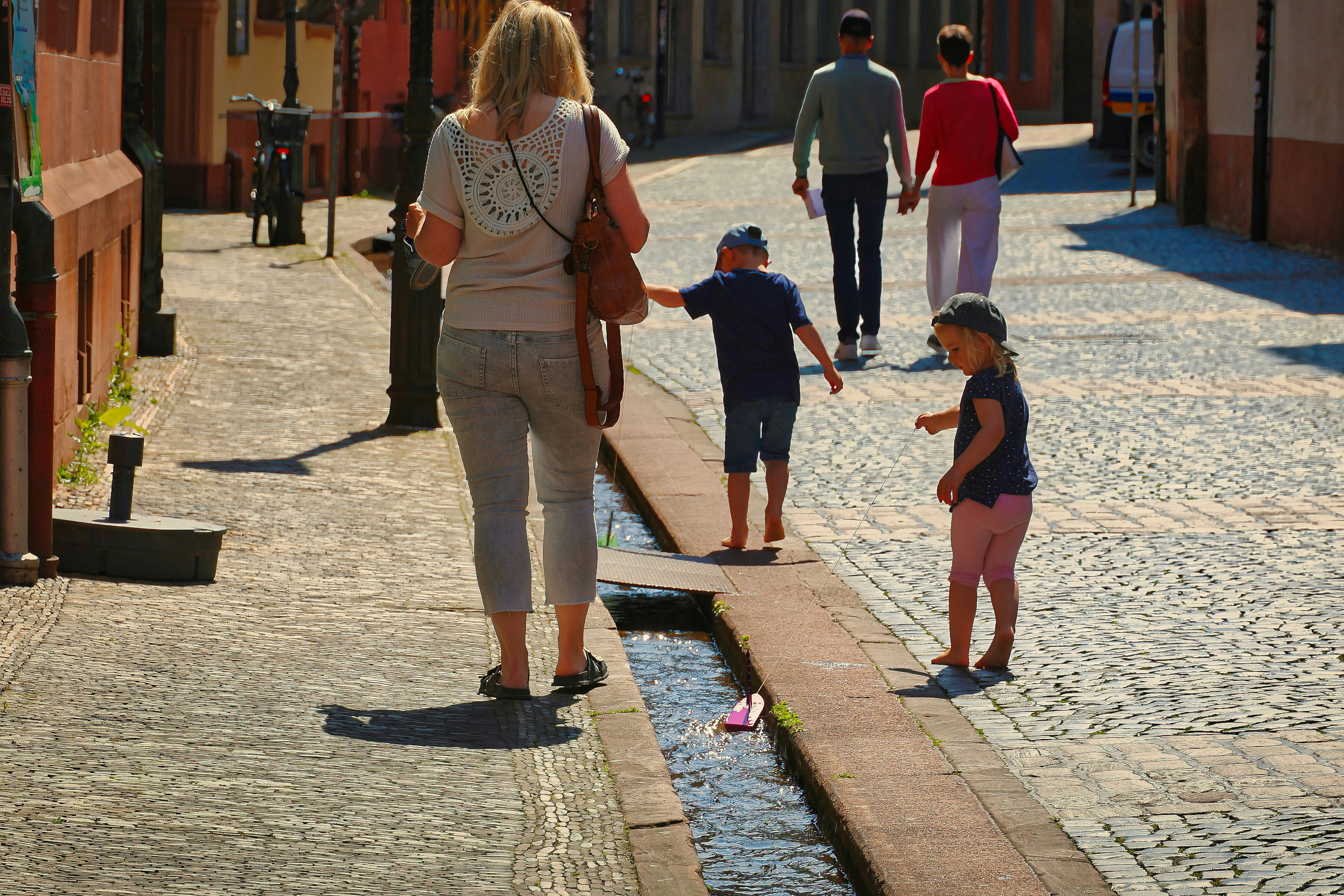 Family walks down a cobblestone street with a canal.