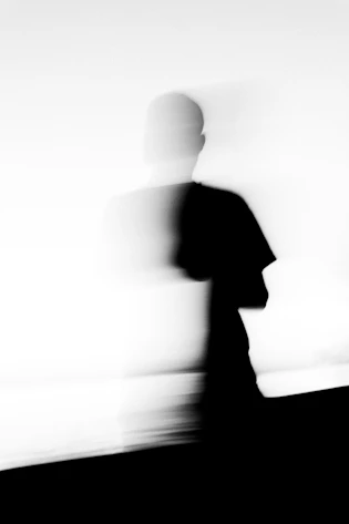 Blurred silhouette of a person walking against a bright background