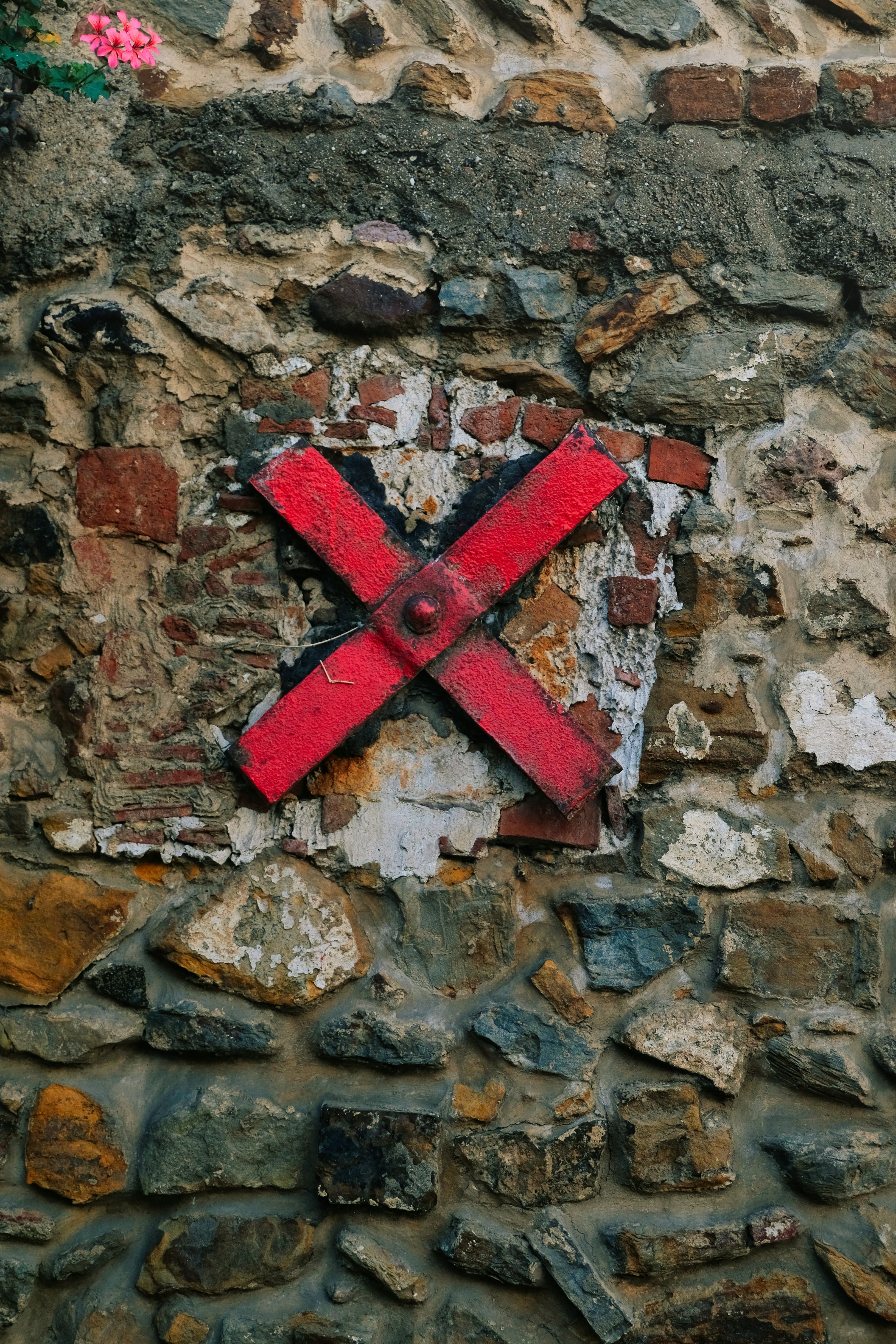 Red x marking on a rustic stone wall
