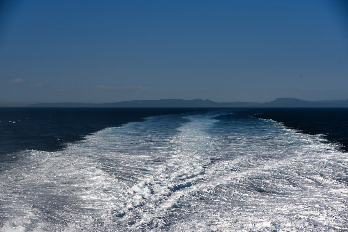 Turbulent wake from a vessel underway — the concentrated jet impingement that propeller wash and bow-thrusters create in the berth pocket