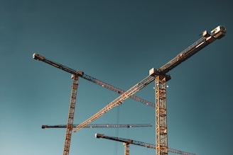 Construction cranes against a clear blue sky