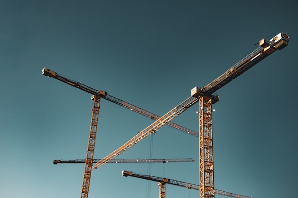 Construction cranes against a clear blue sky