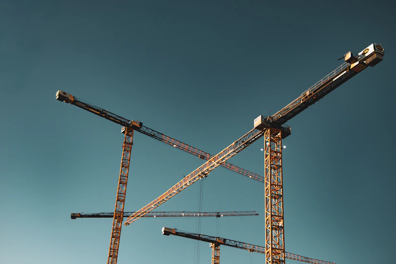Construction cranes against a clear blue sky