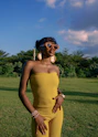 Woman in yellow jumpsuit with heart sunglasses outdoors