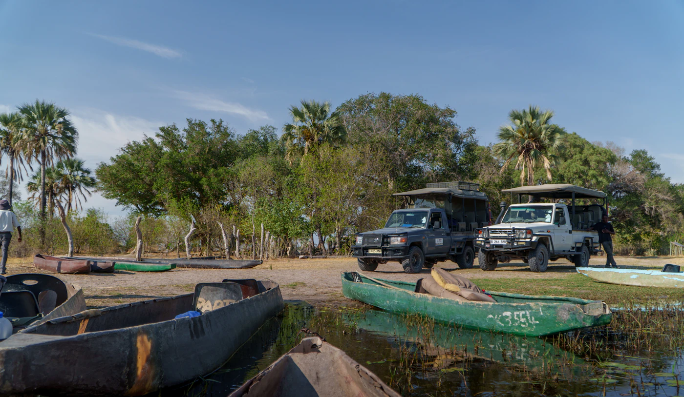 Boats and safari vehicles at the water's edge in Botswana's Okavango Delta during the flood season