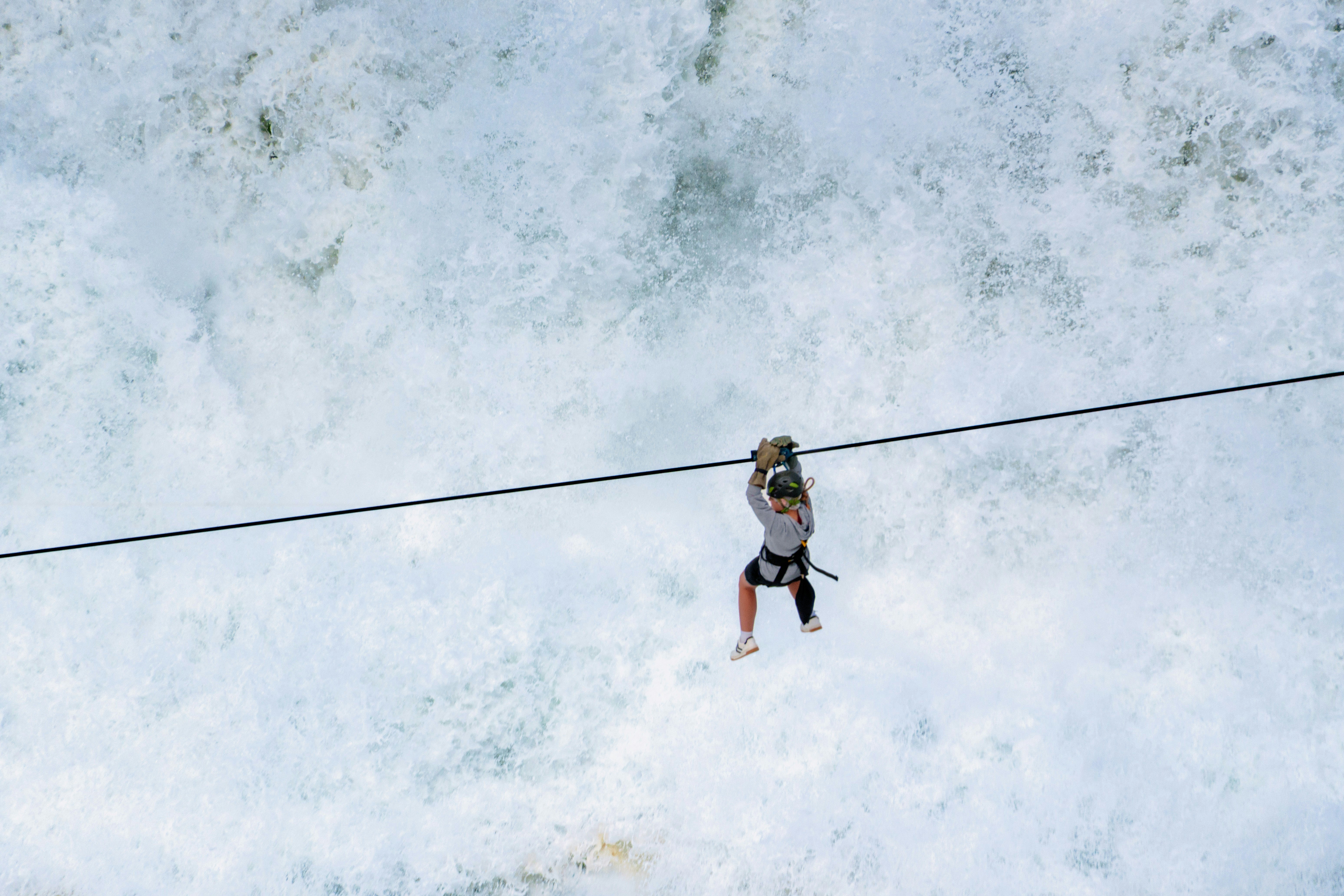 Person ziplining over powerful whitewater rapids
