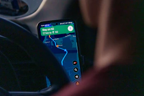 Person using navigation app on smartphone inside car.